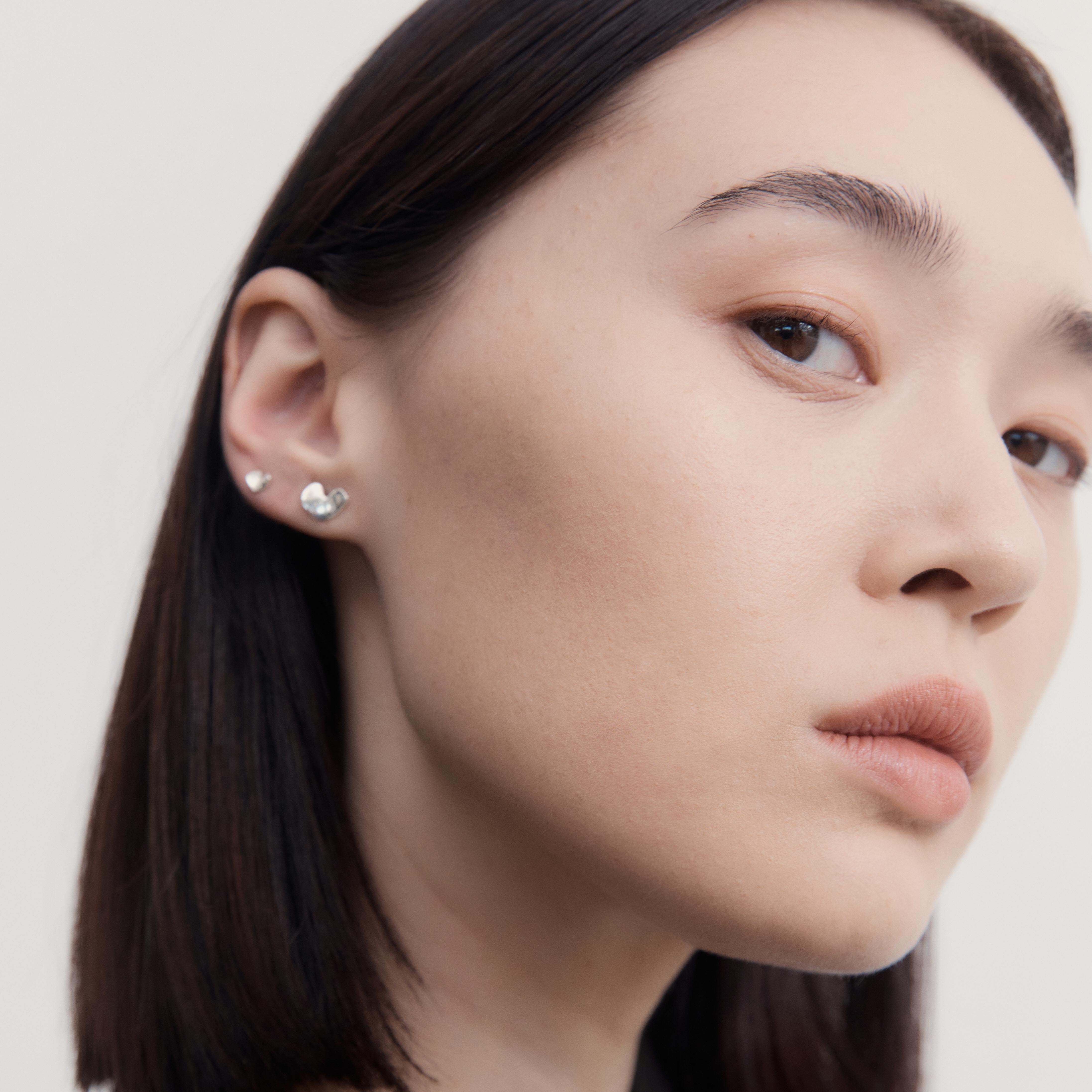 Woman wearing AGMES .925 Sterling Silver Mini Sculpted Heart Stud Earrings 