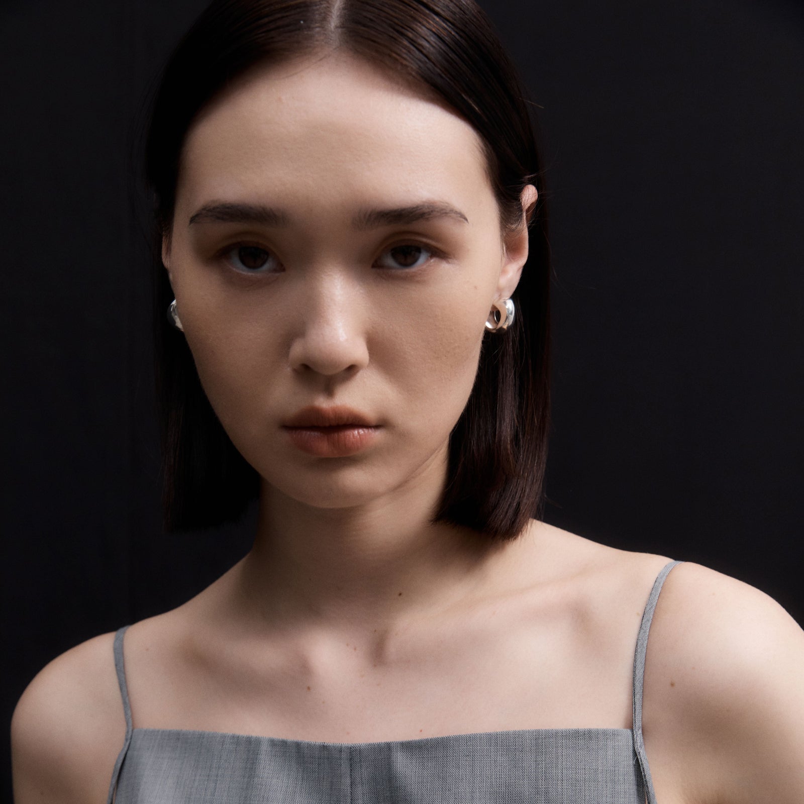 Woman wearing AGMES 0.925 sterling silver small hoop earrings.