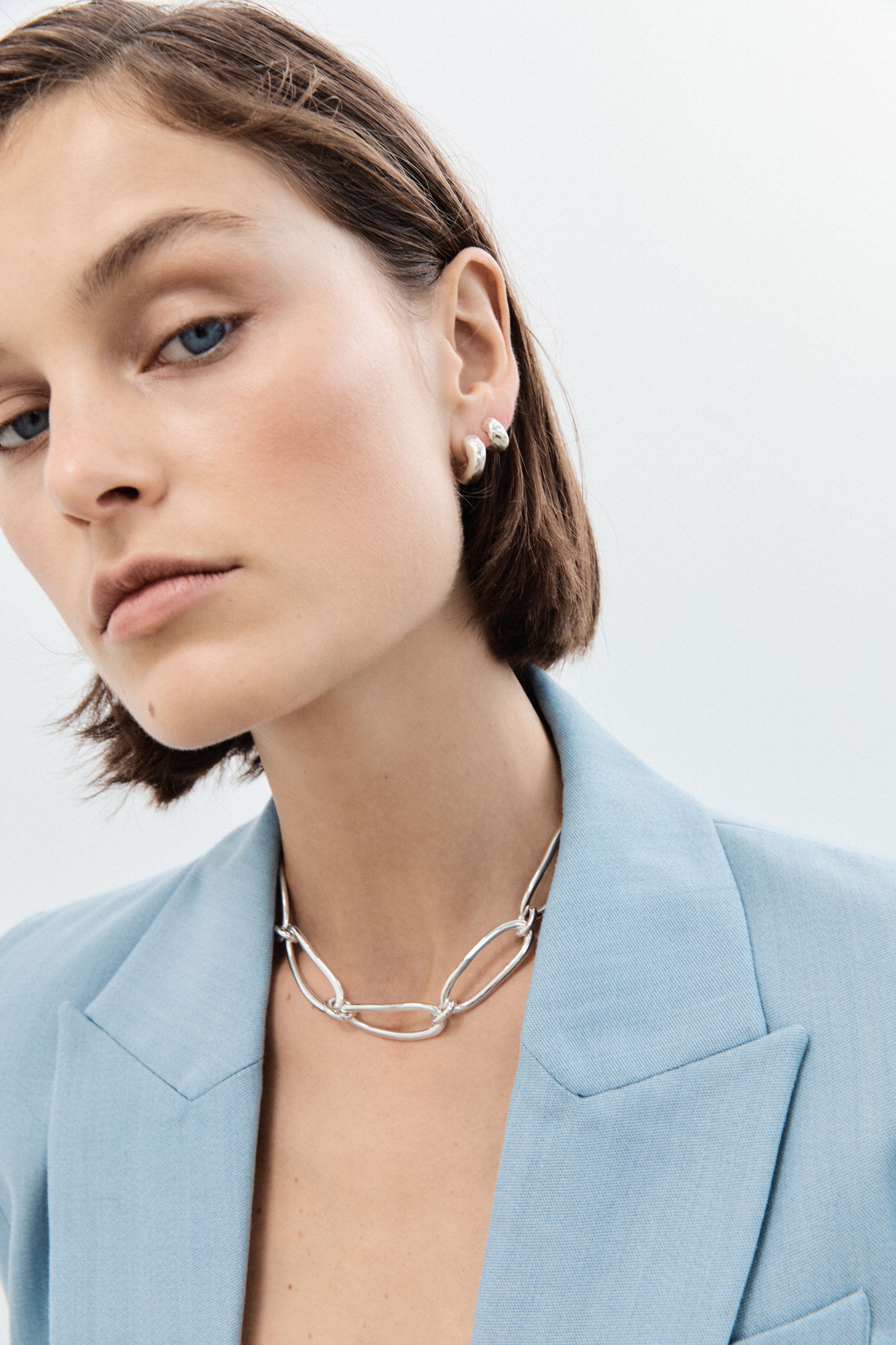 Woman wearing AGMES 0.925 sterling silver thick hoop earrings.