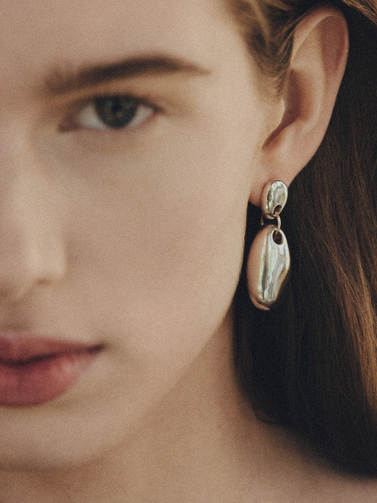 Woman wearing AGMES 0.925 sterling silver sculpted round drop earrings.