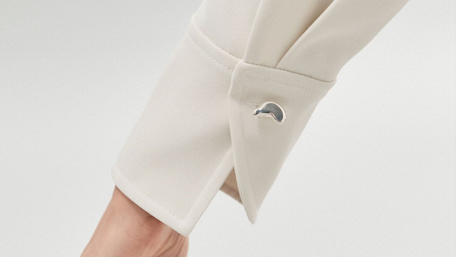 Model wearing AGMES .925 sterling silver sculptural heart Sum of Parts Cufflink on white shirt.