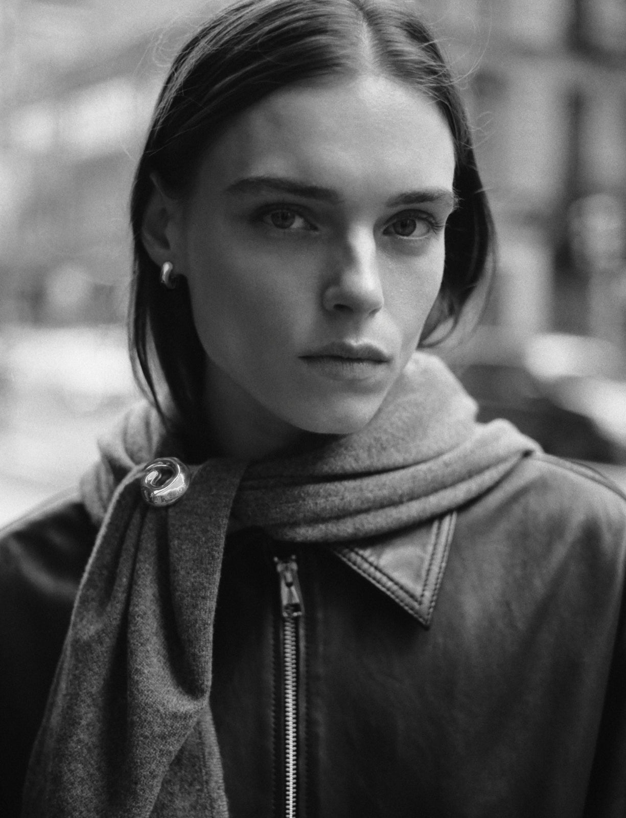 Model wearing AGMES .925 sterling silver sculptural heart spiral Nadia Brooch and Small Dahlia Hoops with knit scarf. Black and white image.