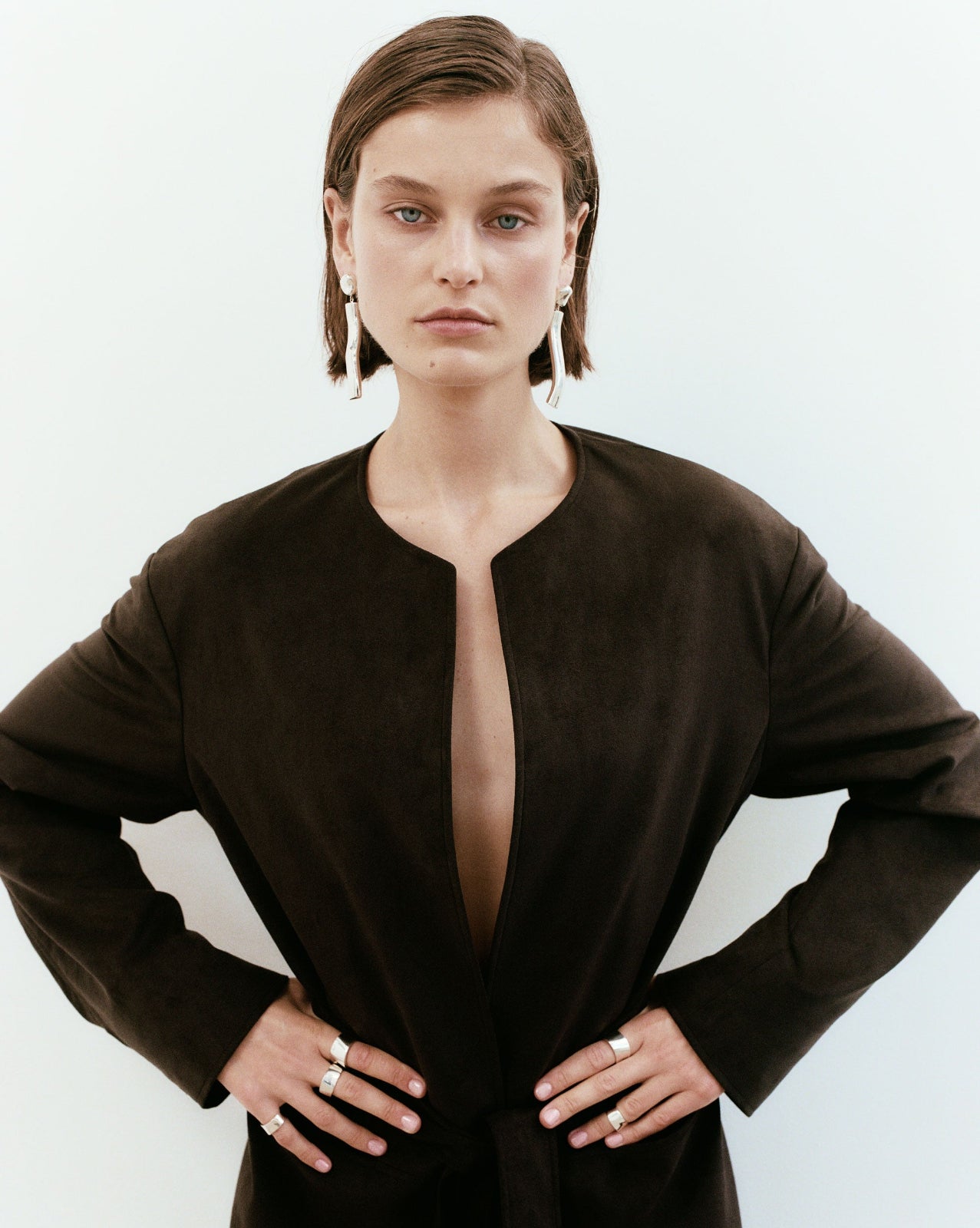 Woman wearing AGMES 0.925 sterling silver long sculptural drop earrings with silver top.