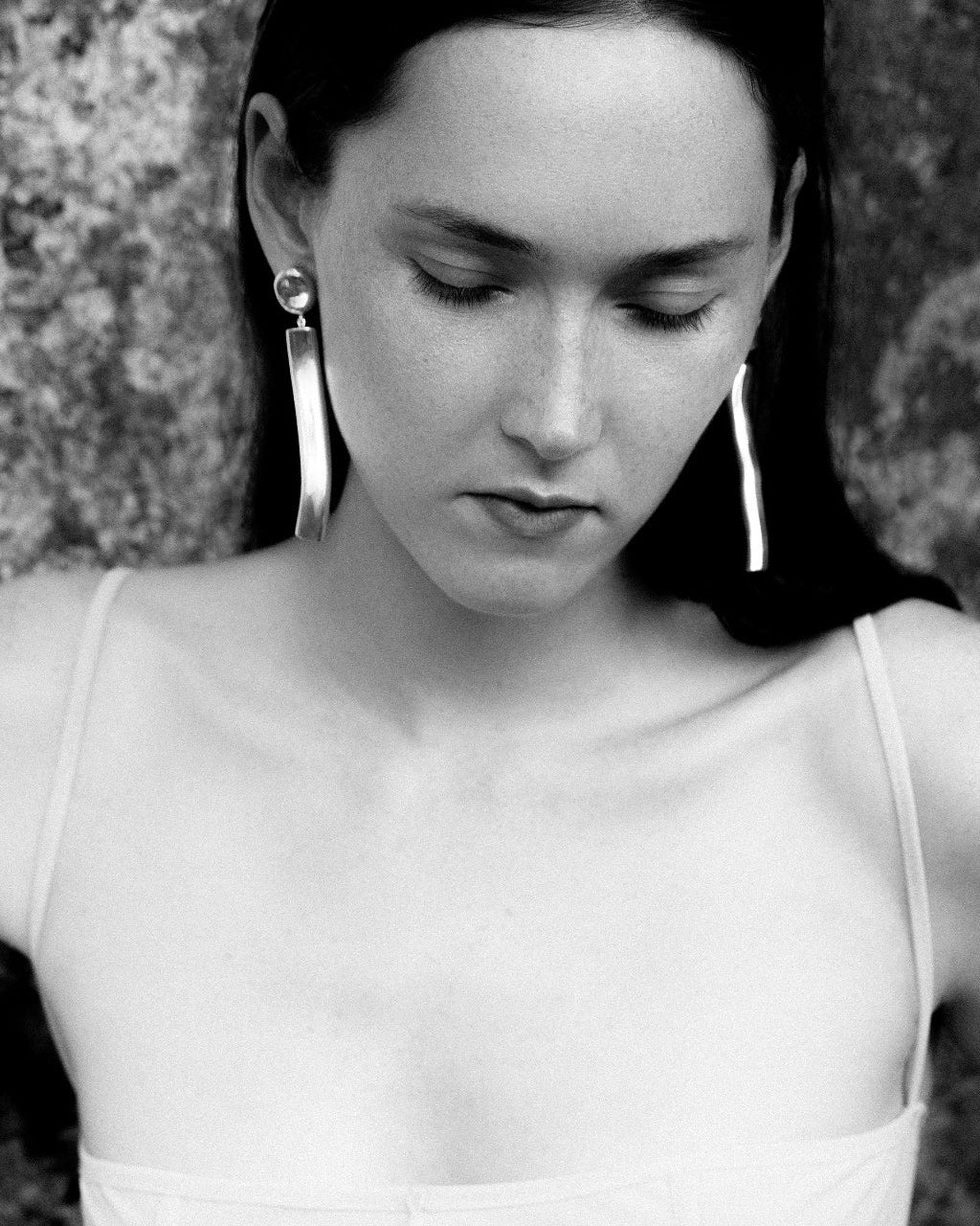 Woman wearing AGMES 0.925 sterling silver long sculptural drop earrings with silver top.