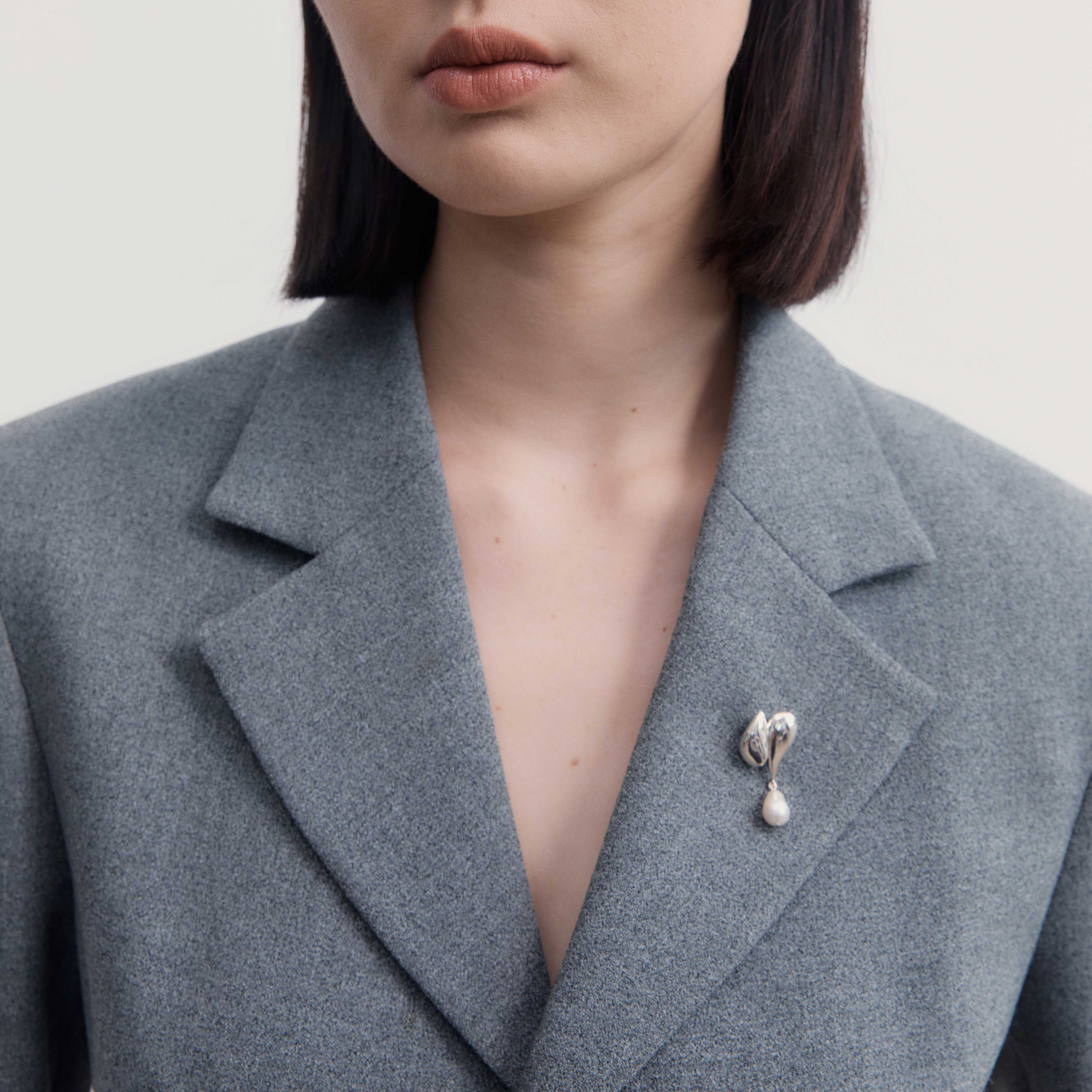 Person wearing AGMES .925 Sterling Silver Elvira Brooch with Baroque drop pearl on grey blazer. 