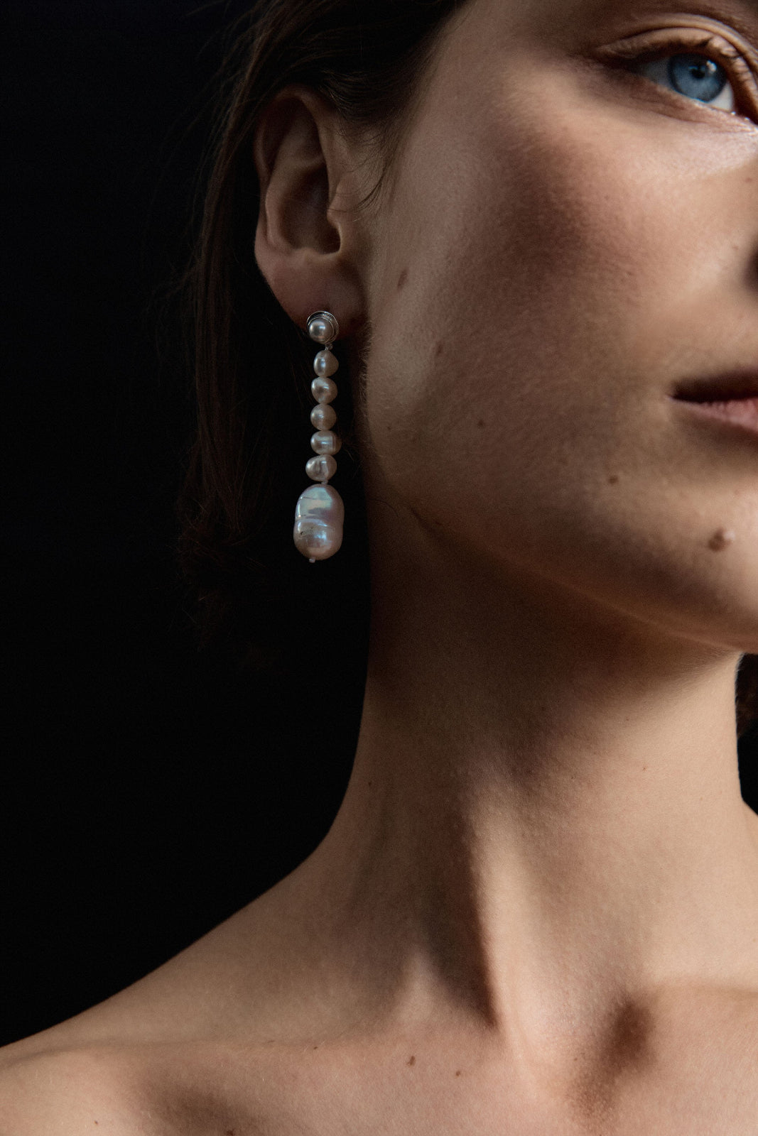 Model wearing AGMES .925 sterling silver and baroque freshwater pearl Emmanuelle Earrings. Black background.