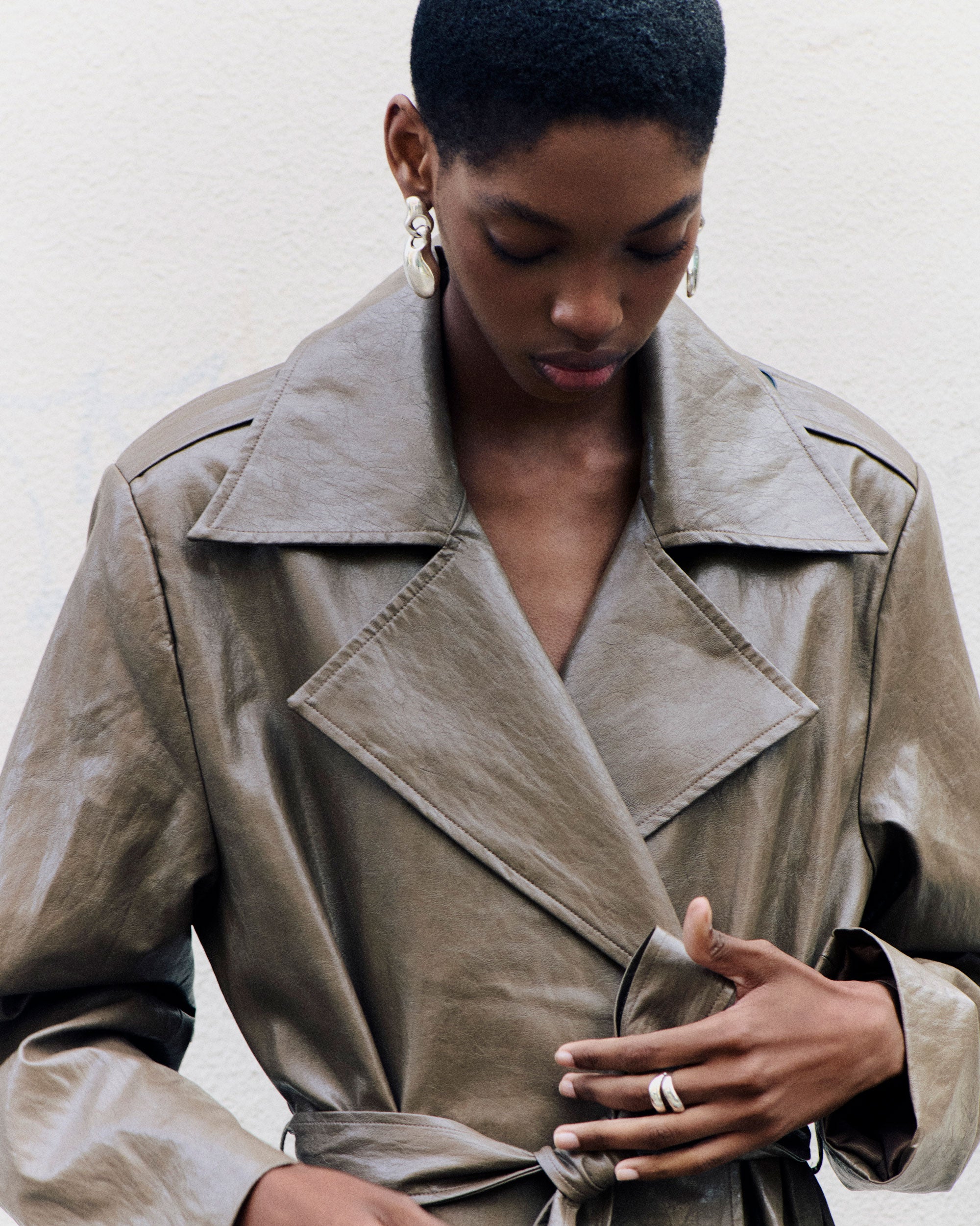 Model wearing .925 sterling silver AGMES double wave ring and francesca earrings with leather trench coat