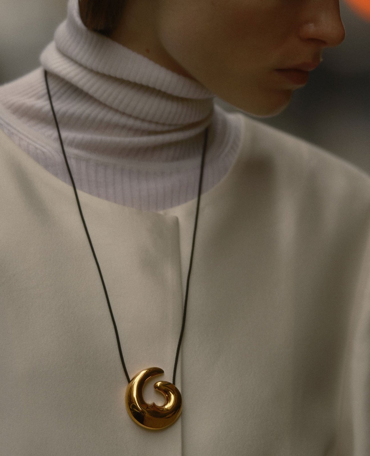 Model wearing 18k gold vermeil Nadia pendant on black suede cord