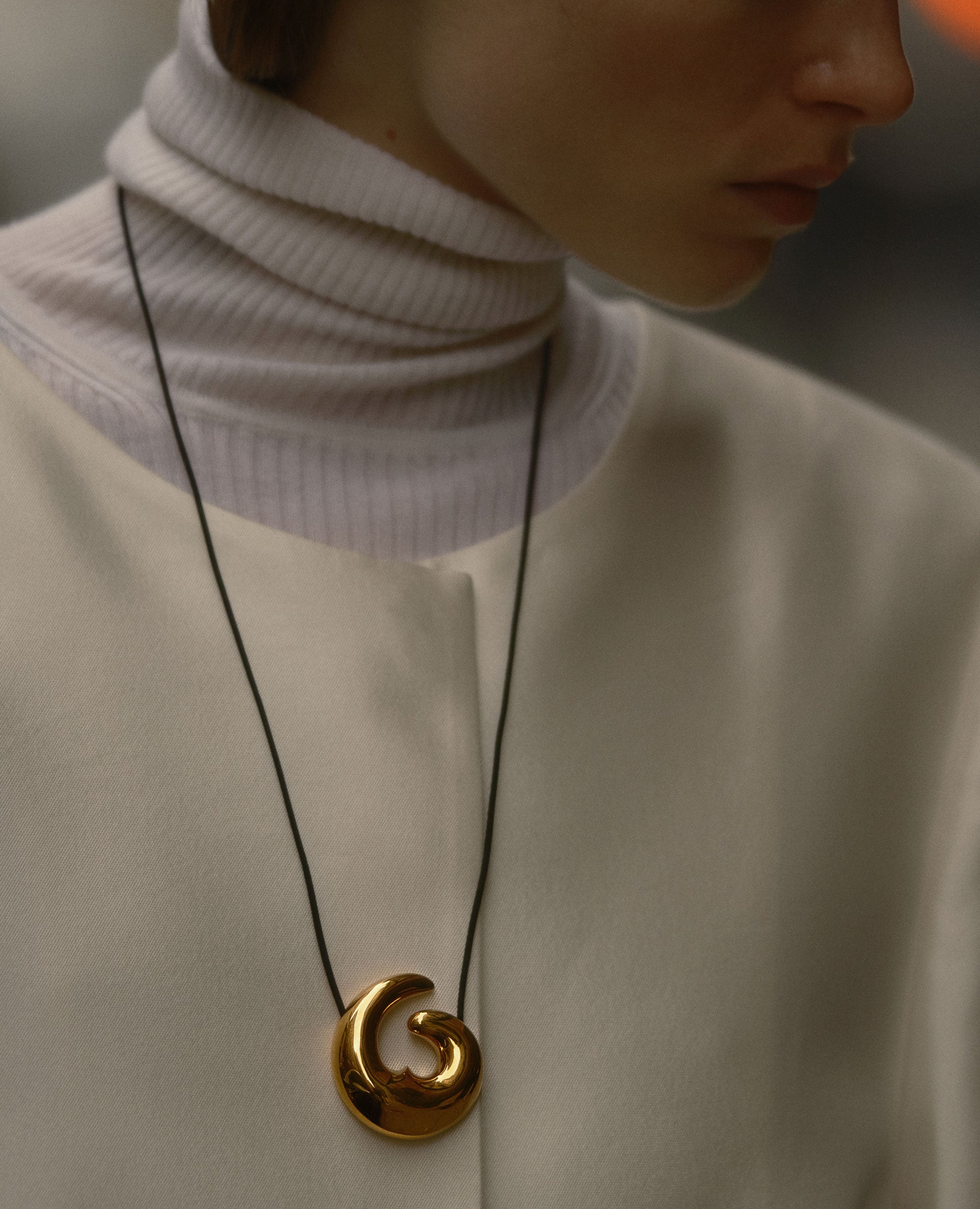 Model wearing 18k gold vermeil Nadia pendant on black suede cord