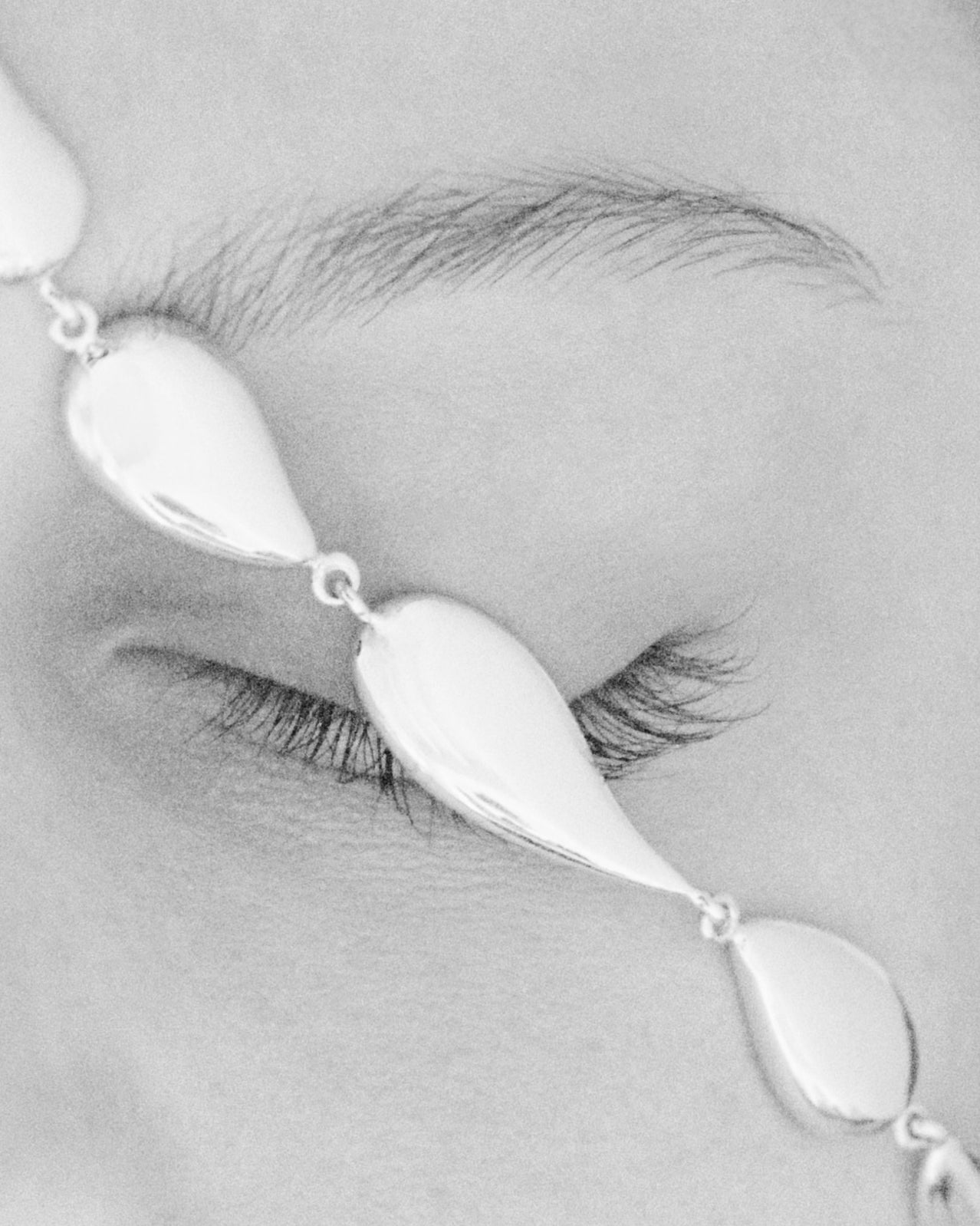 AGMES .925 sterling silver sculptural flora necklace. Photographed in black and white near woman's eye.