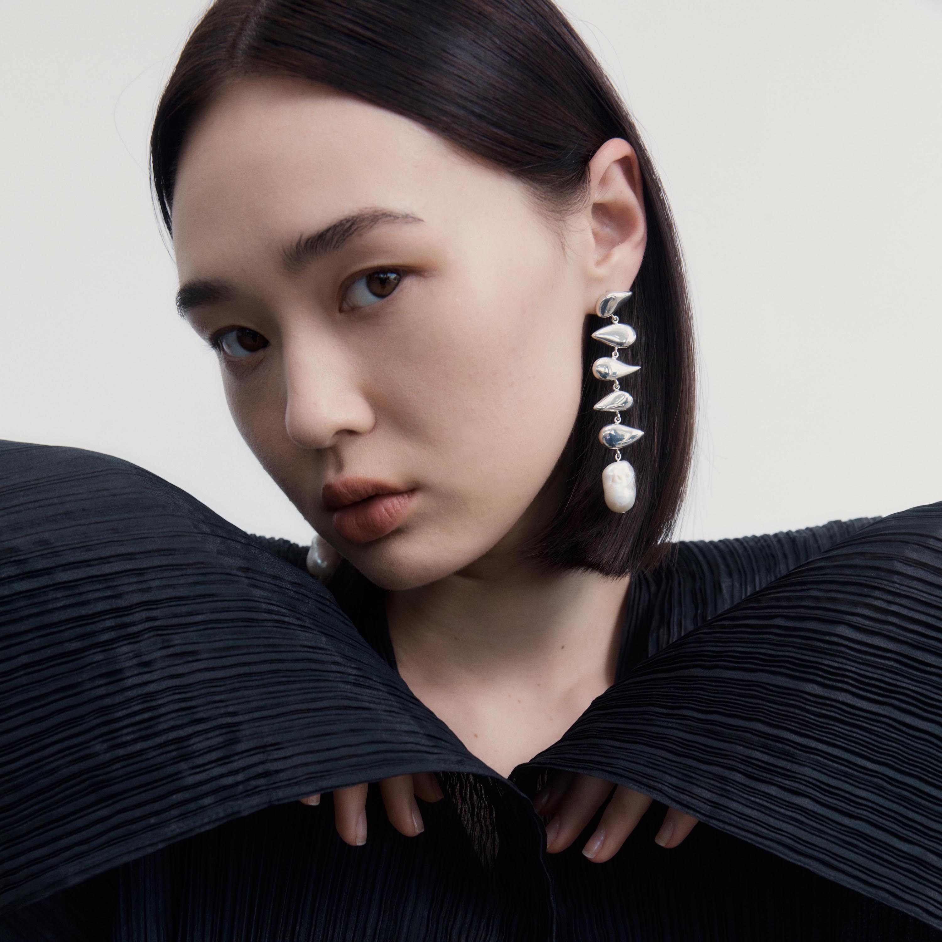 Woman wearing AGMES 0.925 sterling silver long drop pearl Flora earrings.