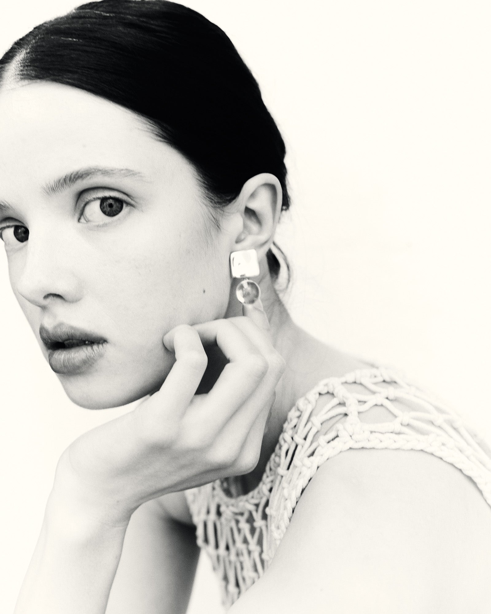 Woman wearing .925 sterling silver square Luca earrings with clear quartz round bead drop, black & white