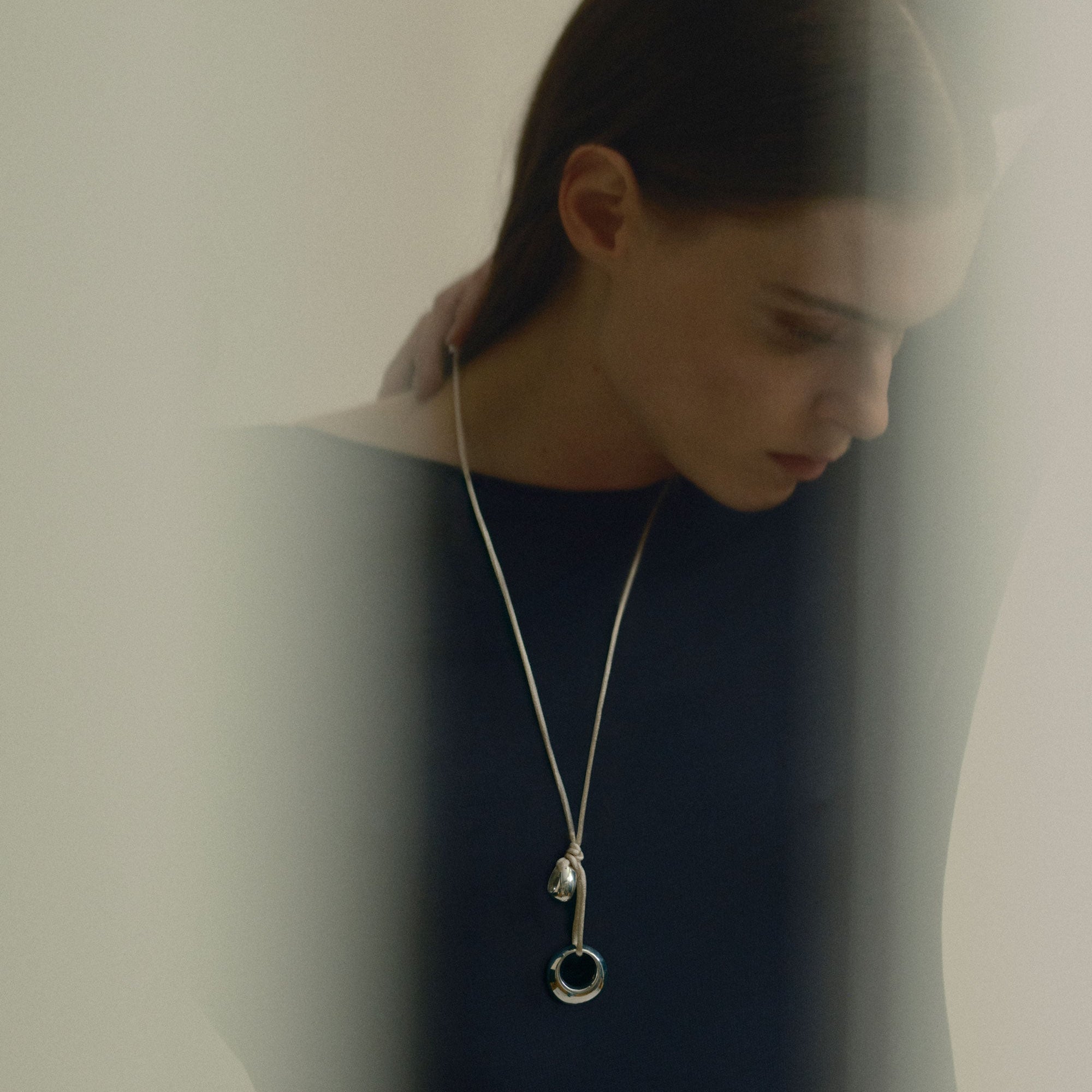 Model wearing AGMES .925 sterling silver Rae pendant on Ivory Silk cord with navy blue blouse.