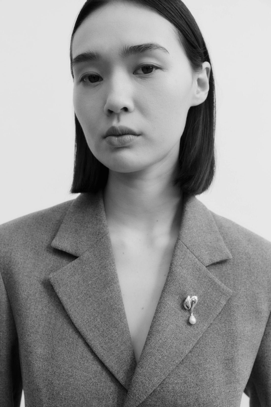 Model wearing sterling silver elvira brooch on lapel with flower petal design and pearl drop