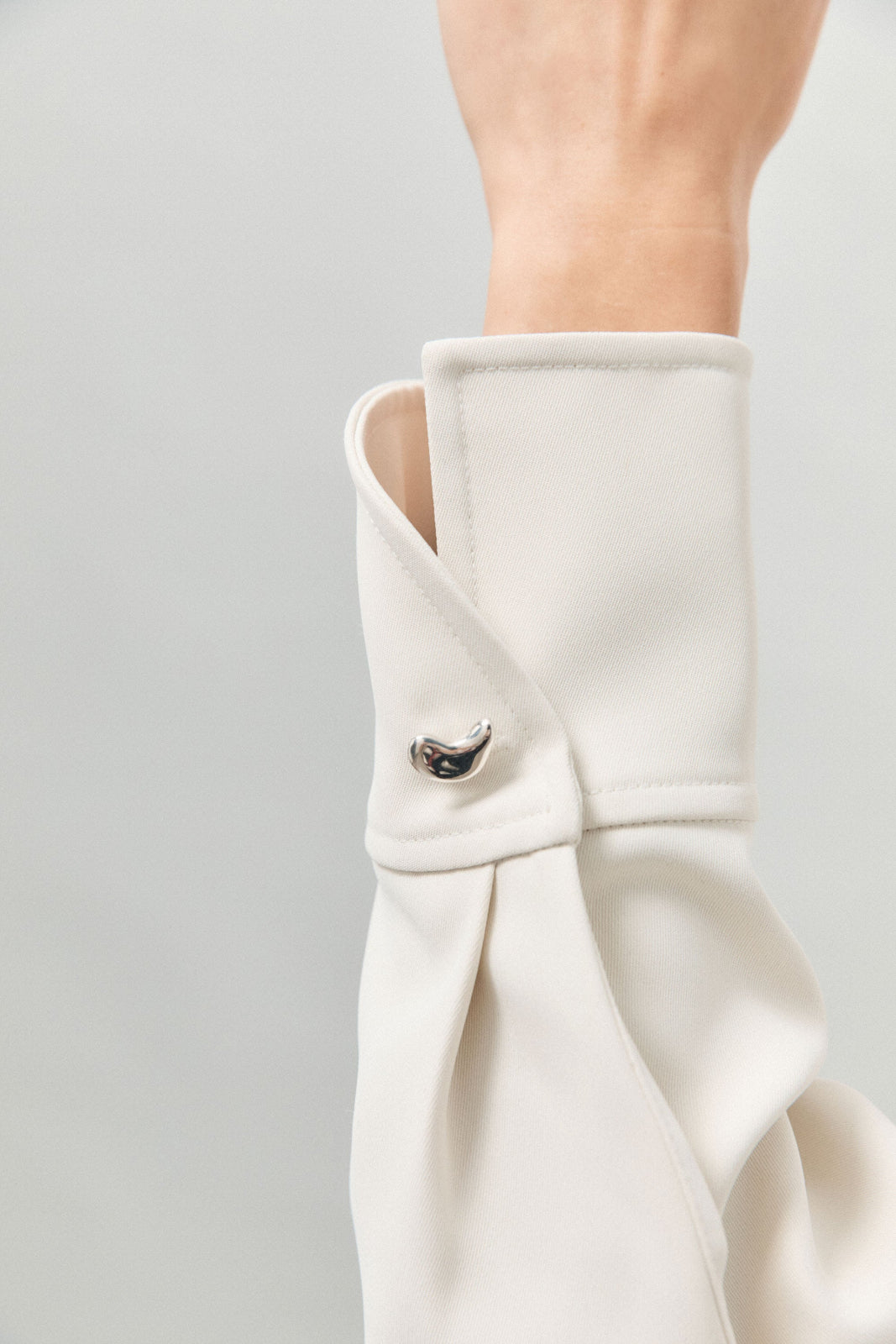 Model wearing AGMES .925 sterling silver sculptural heart Sum of Parts cufflink on white shirt.