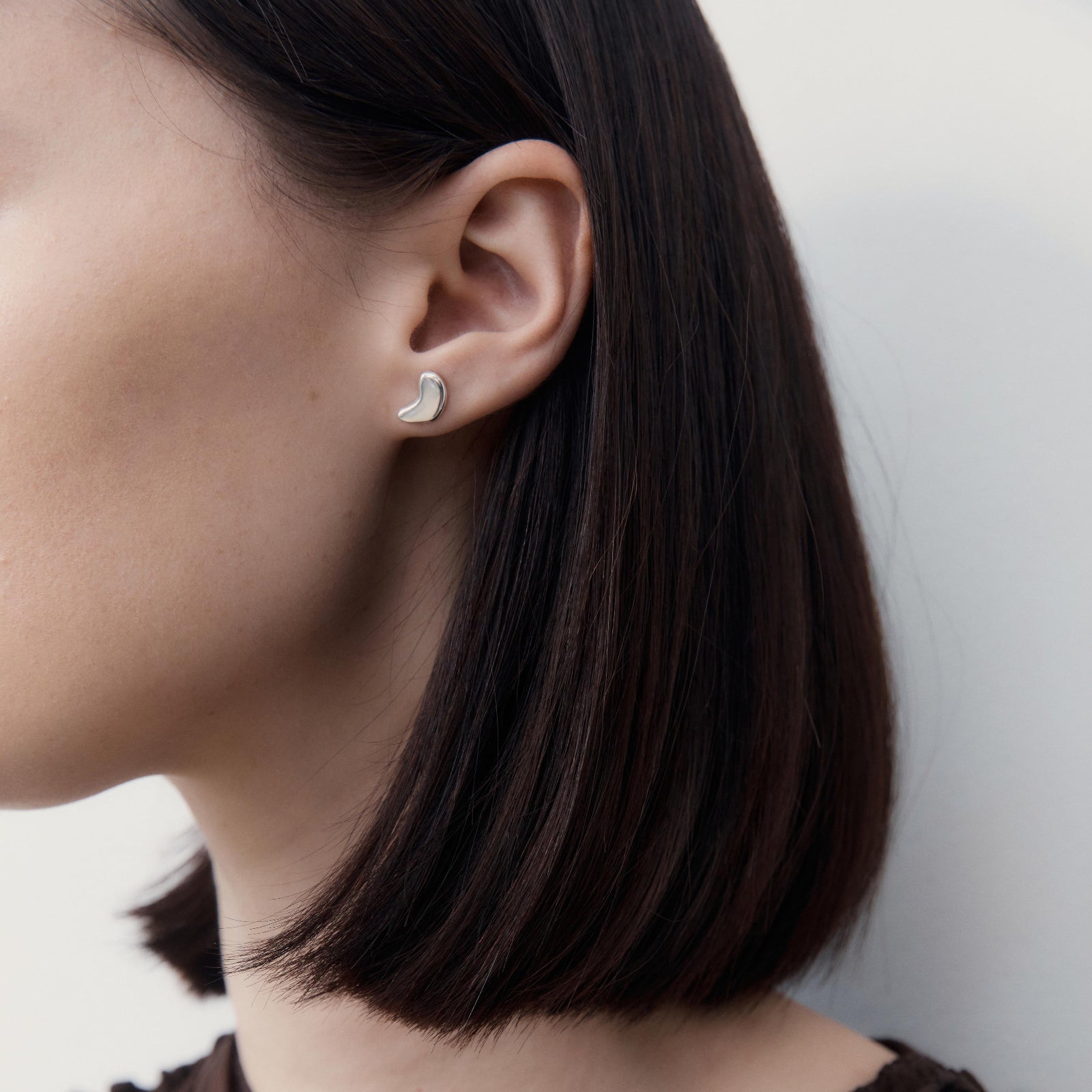 Model wearing AGMES .925 sterling silver sculptural sum of parts heart stud earring.