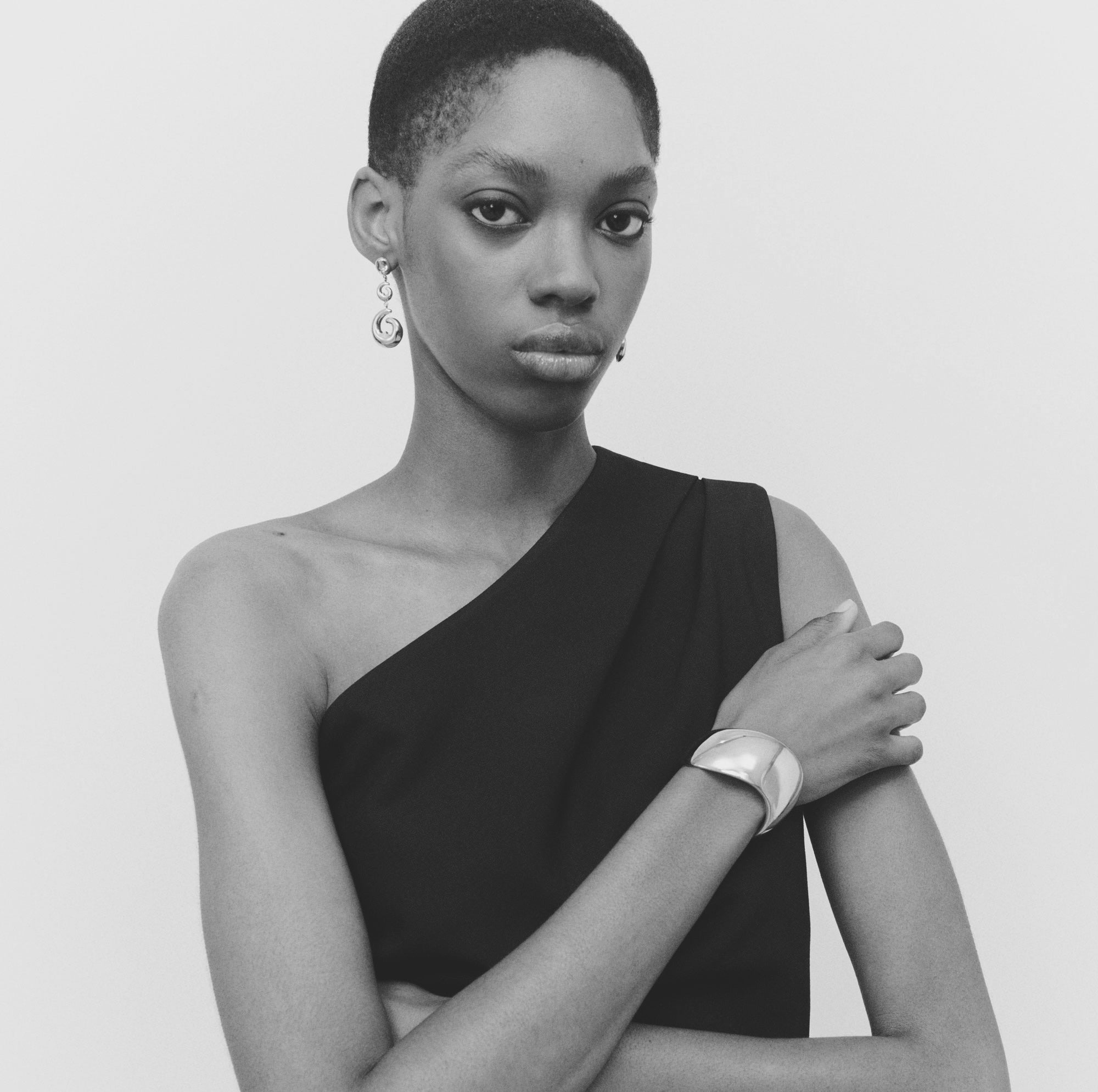 Model wearing curved small Nelle Hoops earrings with fur coat