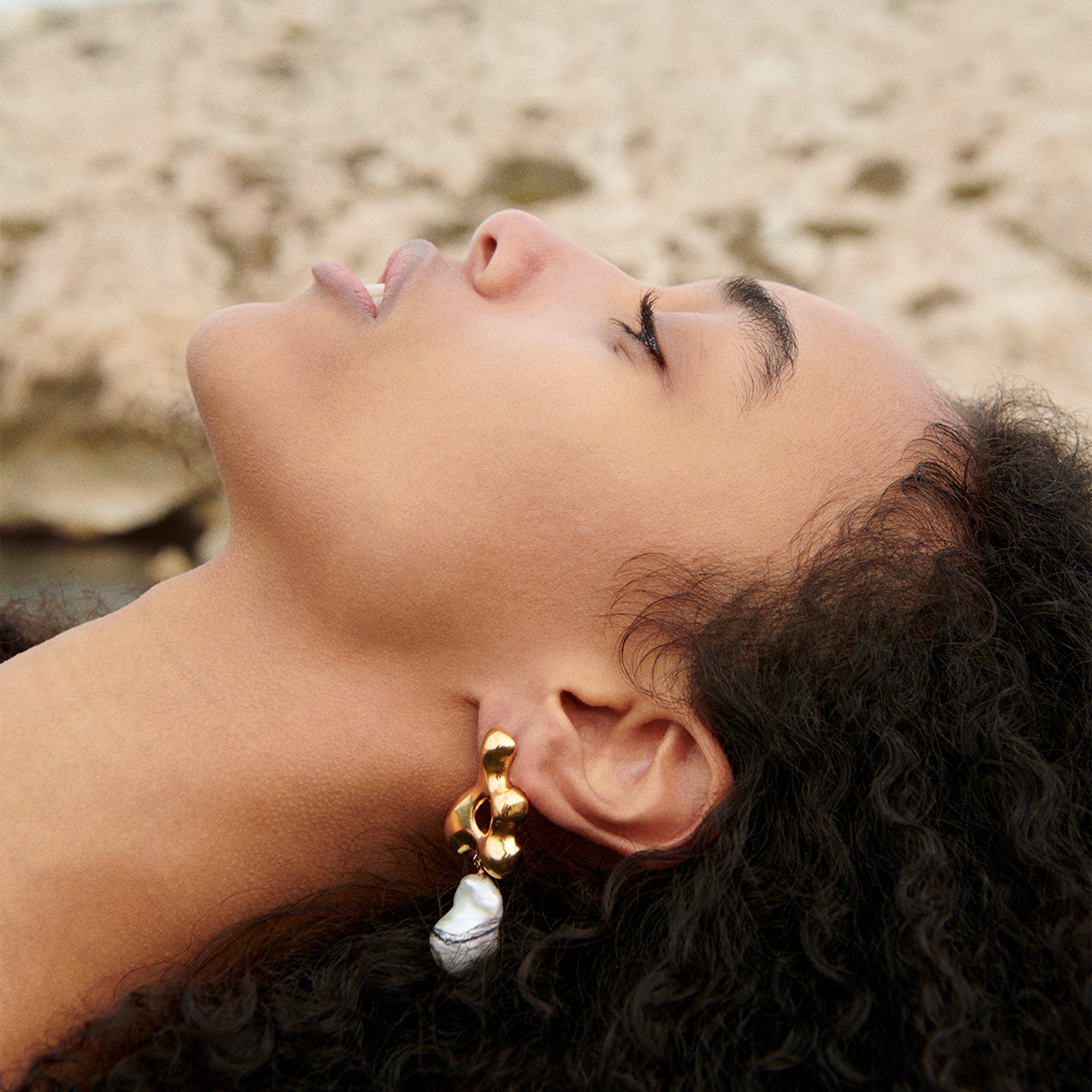 Woman wearing AGMES 18k gold vermeil sculpted earrings with freshwater pearl drop. Simone Bodmer-Turner.