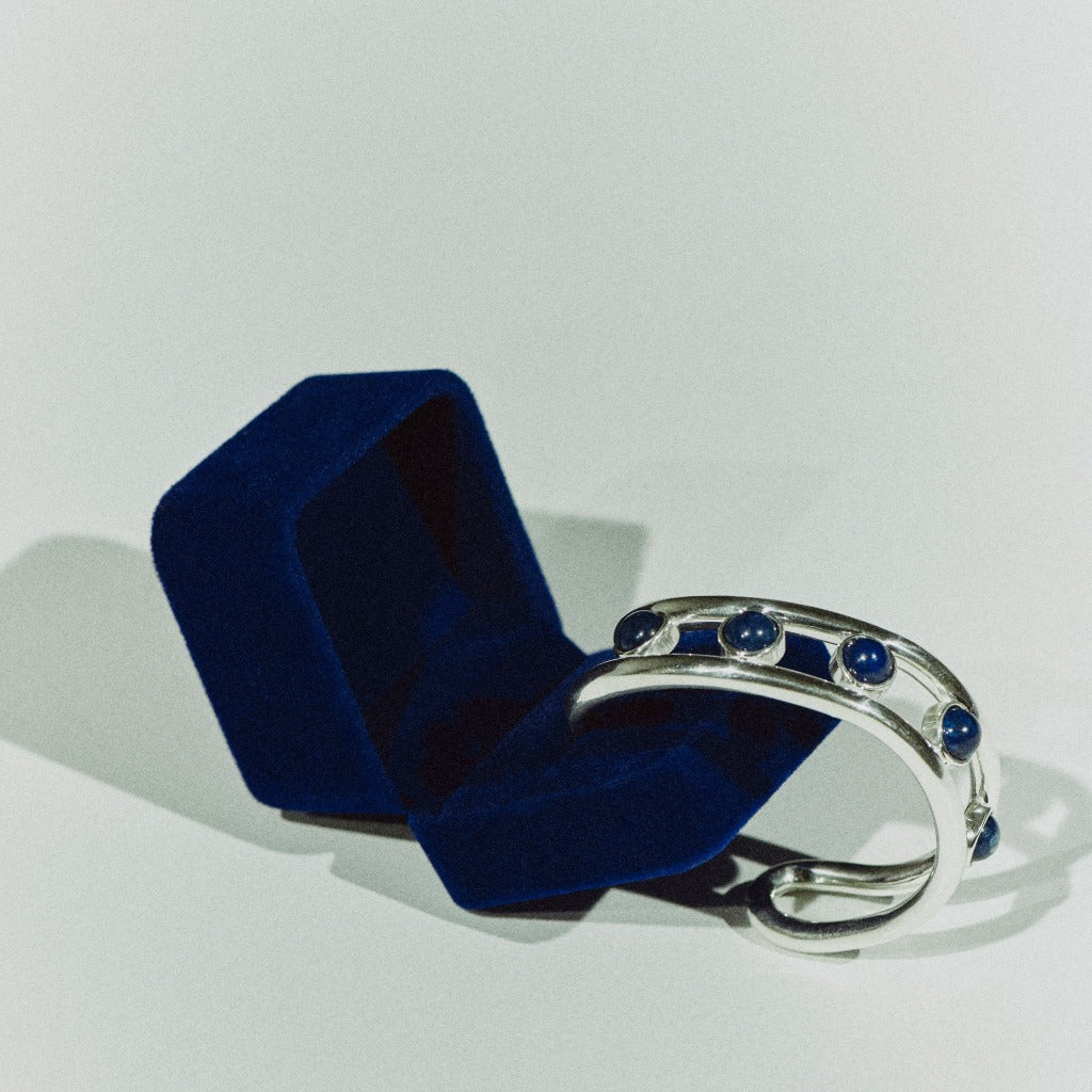 AGMES 0.925 sterling silver Cara cuff bracelet with lapis stones in blue suede box on white background.