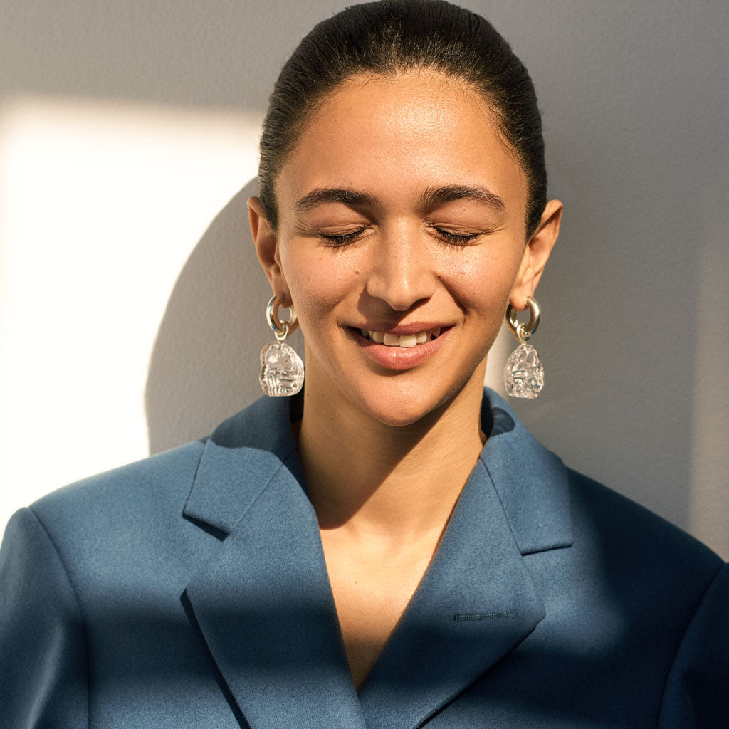 Woman wearing AGMES 0.925 sterling silver hoop earrings with clear Handblown Venetian Glass drop.