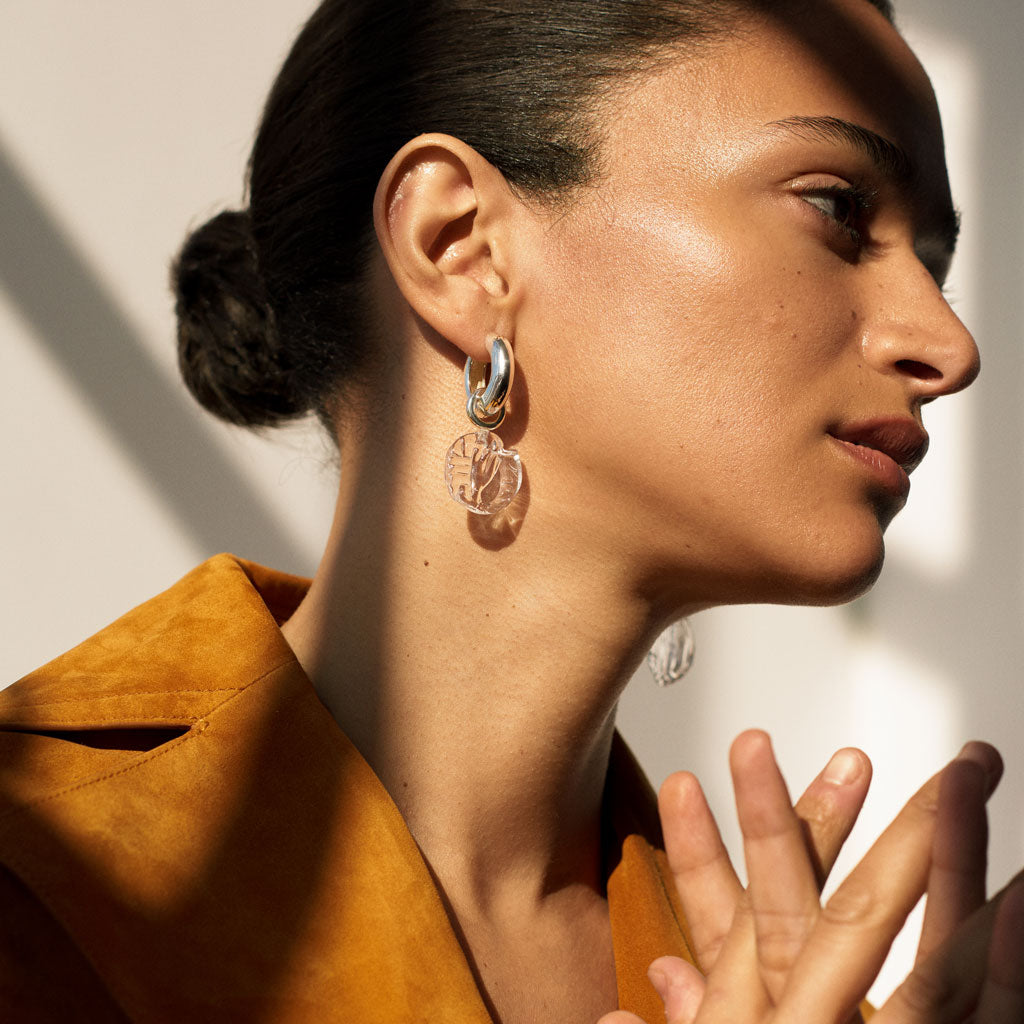 Woman wearing AGMES .925 sterling silver hoop earrings with clear glass bead drop.