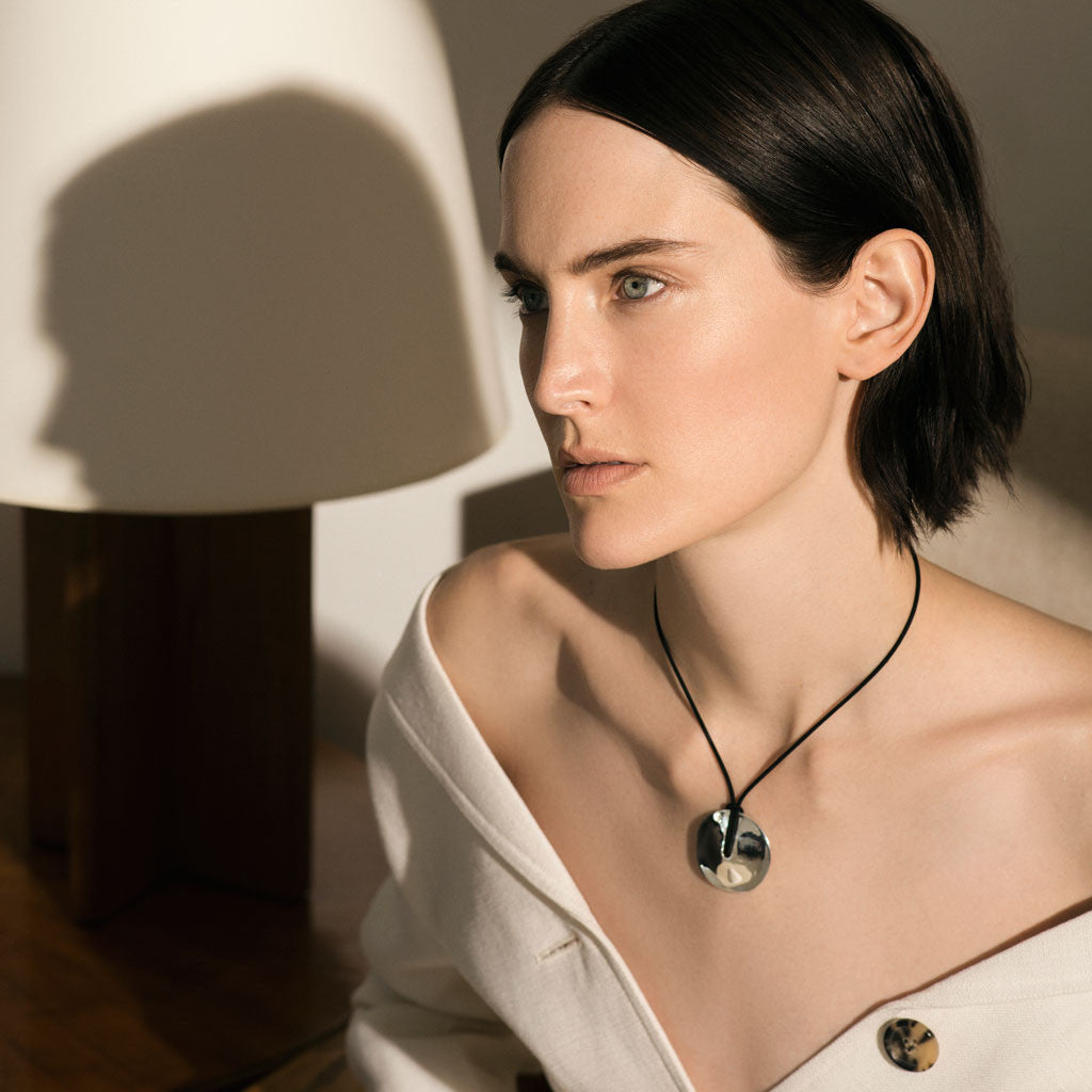 Woman wearing AGMES 0.925 Sterling Silver Cora Pendant paired with Black Suede Cord. Round Pendant Necklace. 