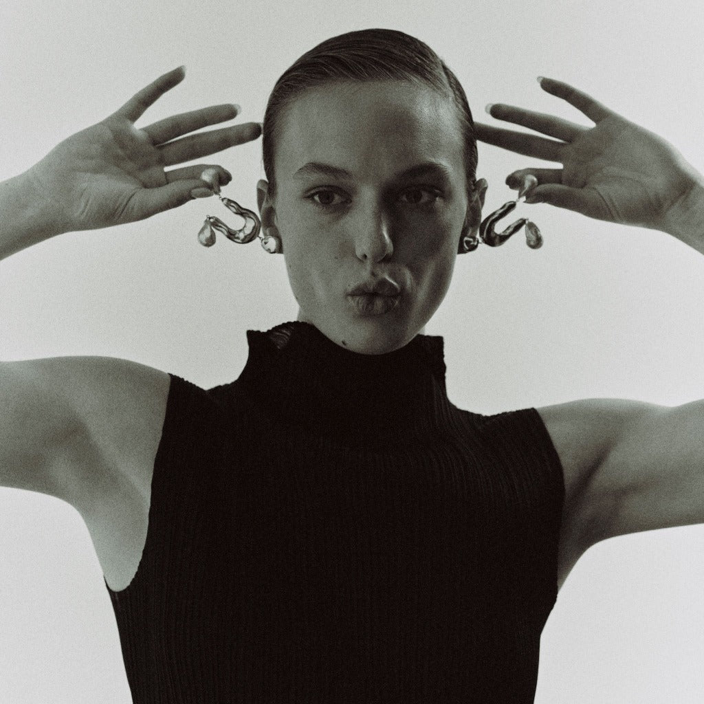 Woman wearing AGMES 0.925 sterling silver earrings with sculpted wishbone and freshwater pearl drop.