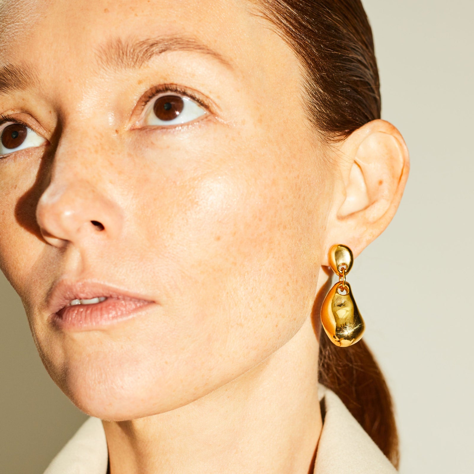 Woman wearing AGMES 18k gold vermeil sculpted round drop earrings.