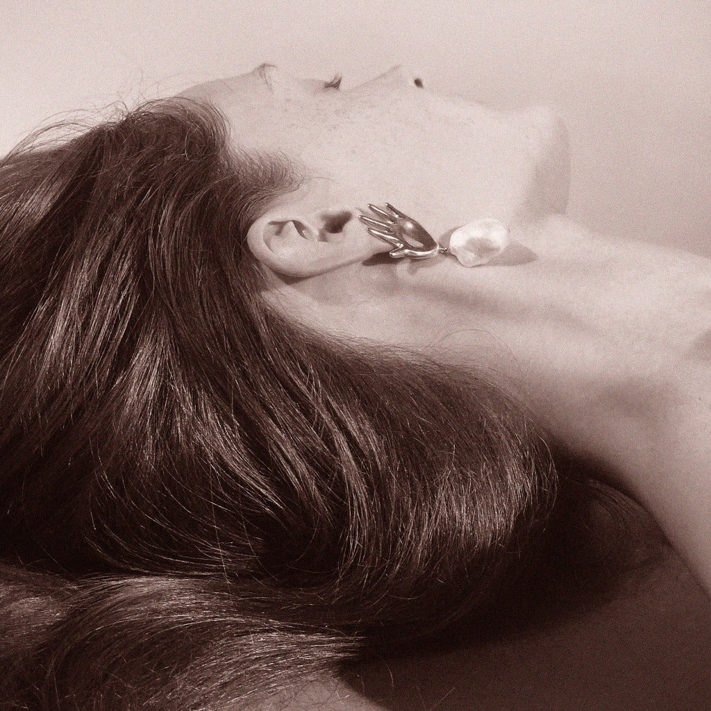 Woman wearing AGMES 0.925 sterling silver abstract hand earrings with baroque freshwater pearl drop.