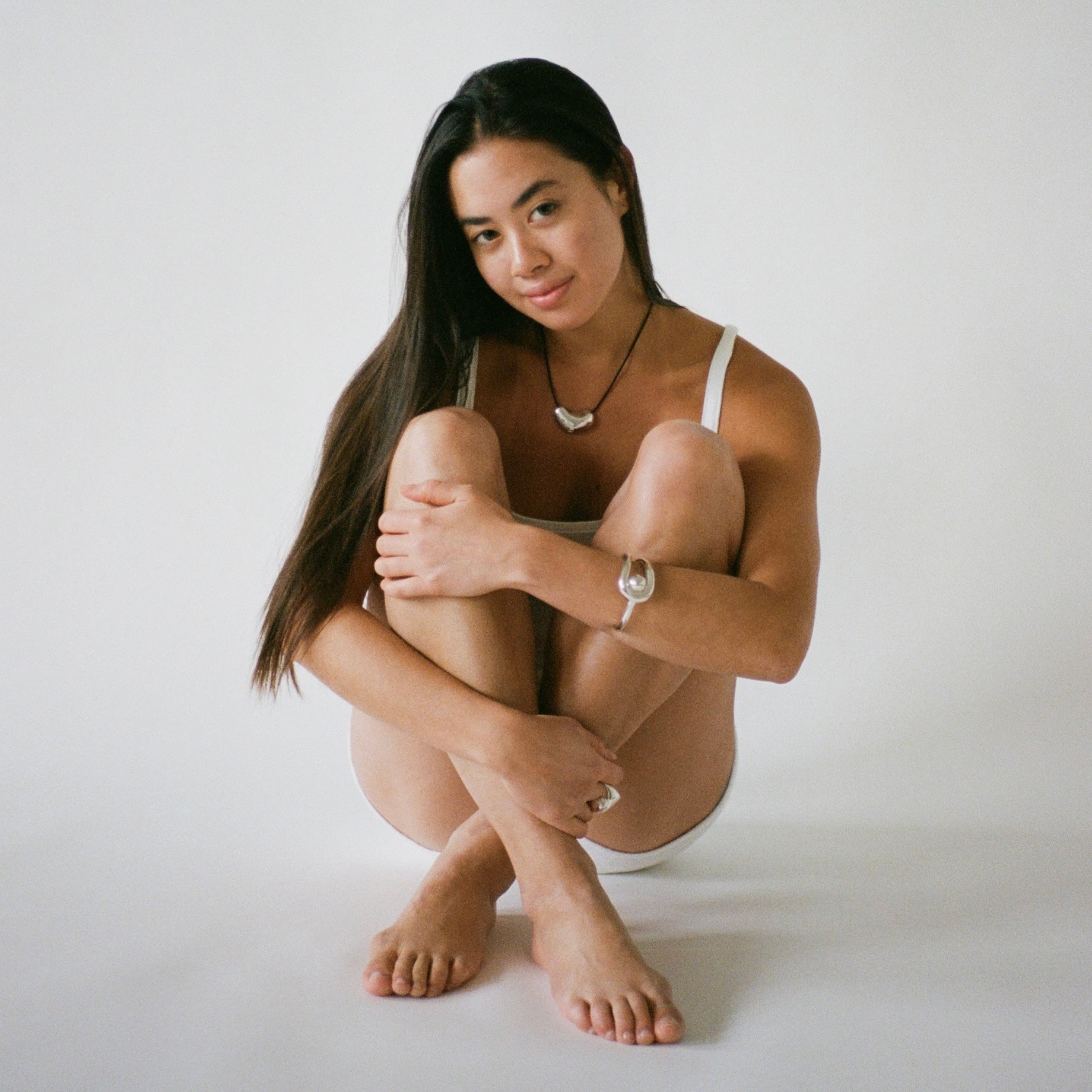Woman wearing AGMES .925 Sterling Silver Sculpted Heart Pendant on Black Suede Cord, Turner Ring, and Becky Cuff with Pearl. 