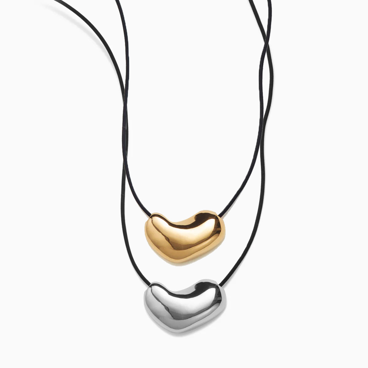 AGMES Sculpted Heart Pendant Set. 925 Sterling Silver Sculpted Heart Pendant on Black Suede Cord paired in a set with 18K Gold Vermeil Sculpted Heart Pendant. 