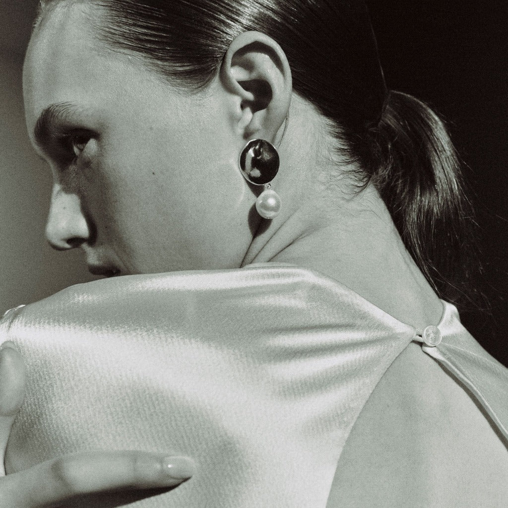 Woman wearing AGMES 0.925 sterling silver disc earrings with freshwater pearl drop.