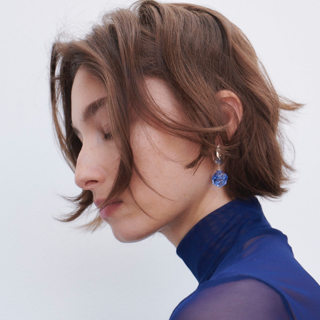 Woman wearing AGMES 0.925 sterling silver small Cleo hoop earrings with blue glass bead drop.