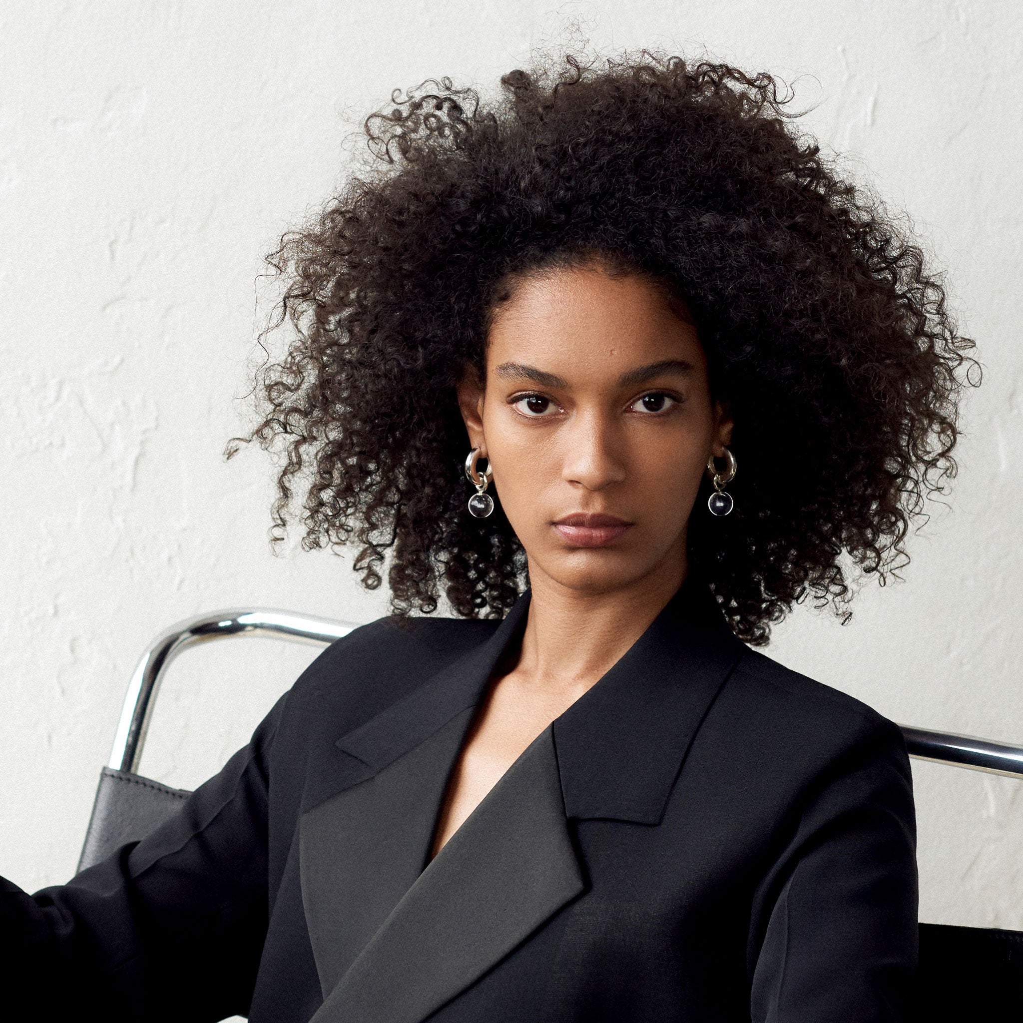 Woman wearing AGMES 0.925 sterling silver Sonia hoops with clear quartz drop embellishments.