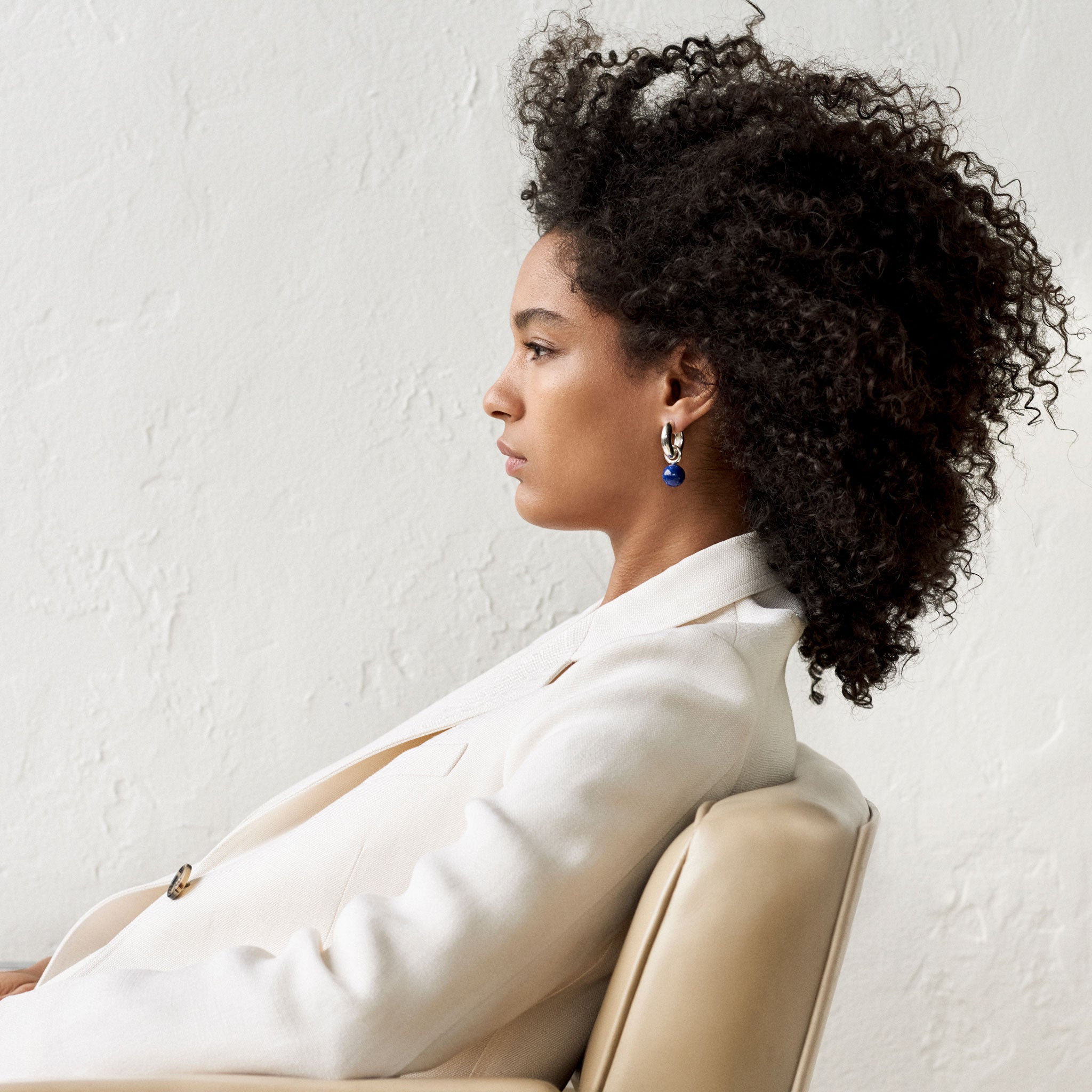 Woman wearing AGMES 0.925 sterling silver Sonia hoops with lapis drop embellishments.