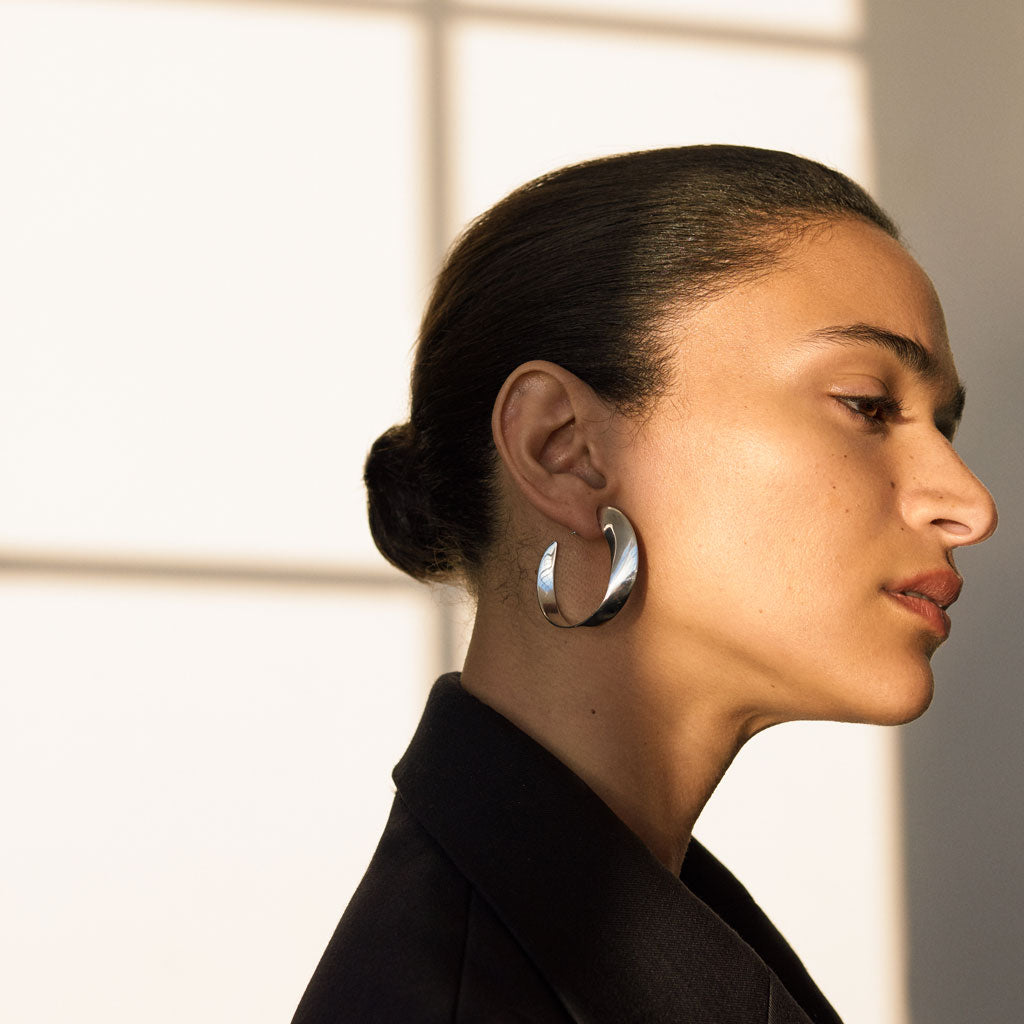Woman wearing AGMES 0.925 sterling silver twist hoop earrings.