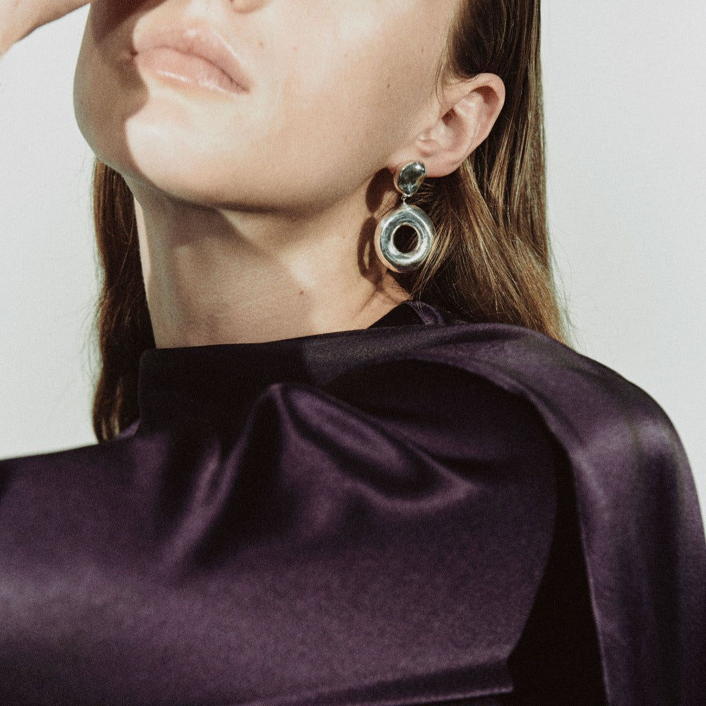 Woman wearing AGMES 0.925 sterling silver earrings with silver drop donut ring.