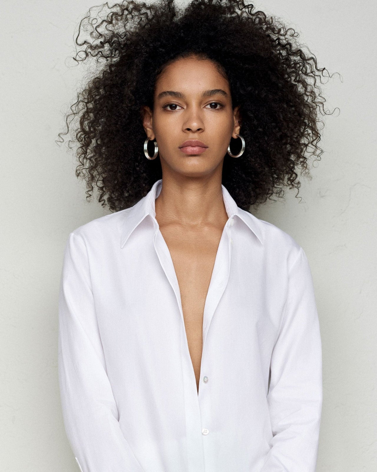 Woman wearing AGMES 0.925 sterling silver double ridged large hoop earrings.