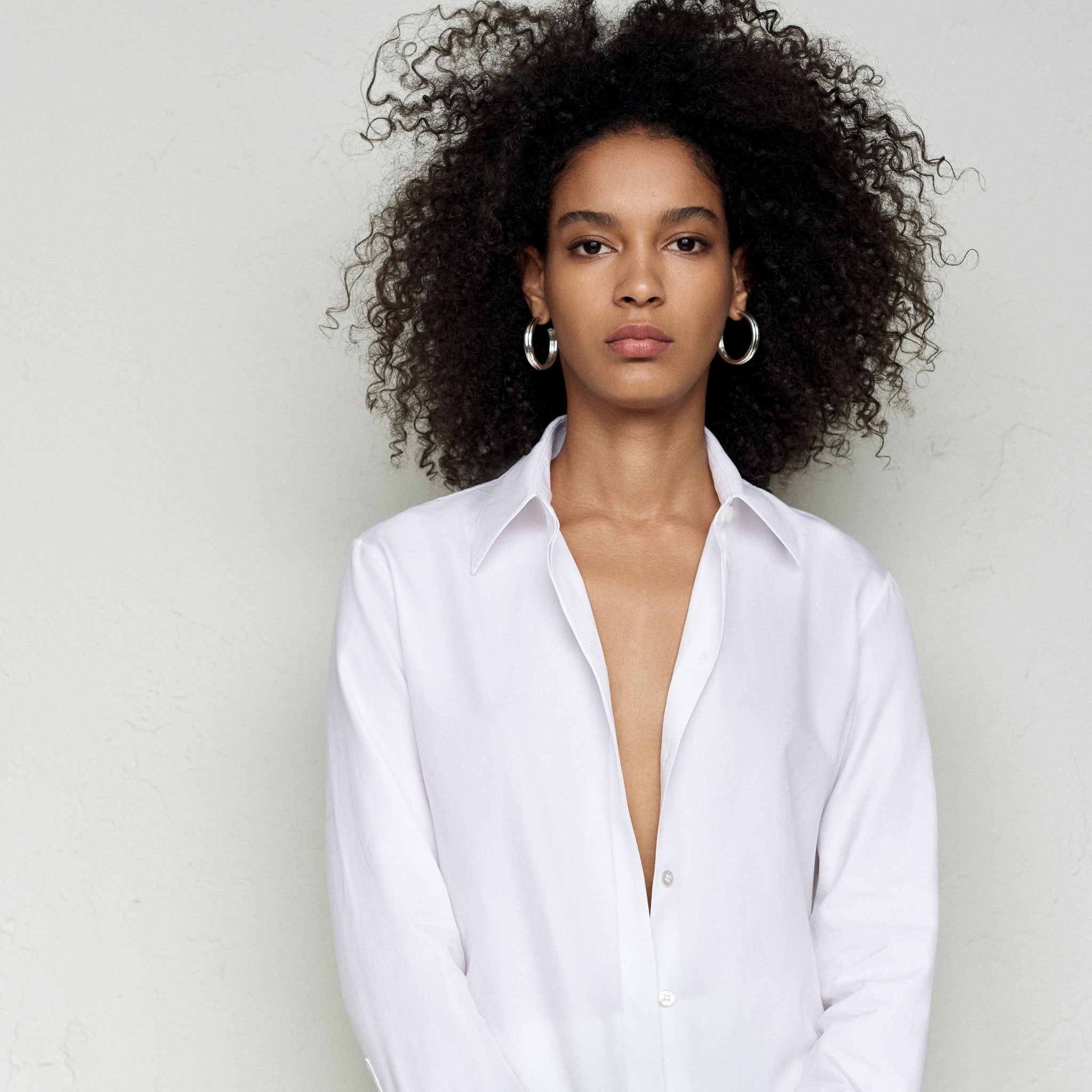 Woman wearing AGMES 0.925 sterling silver double ridged large hoop earrings.