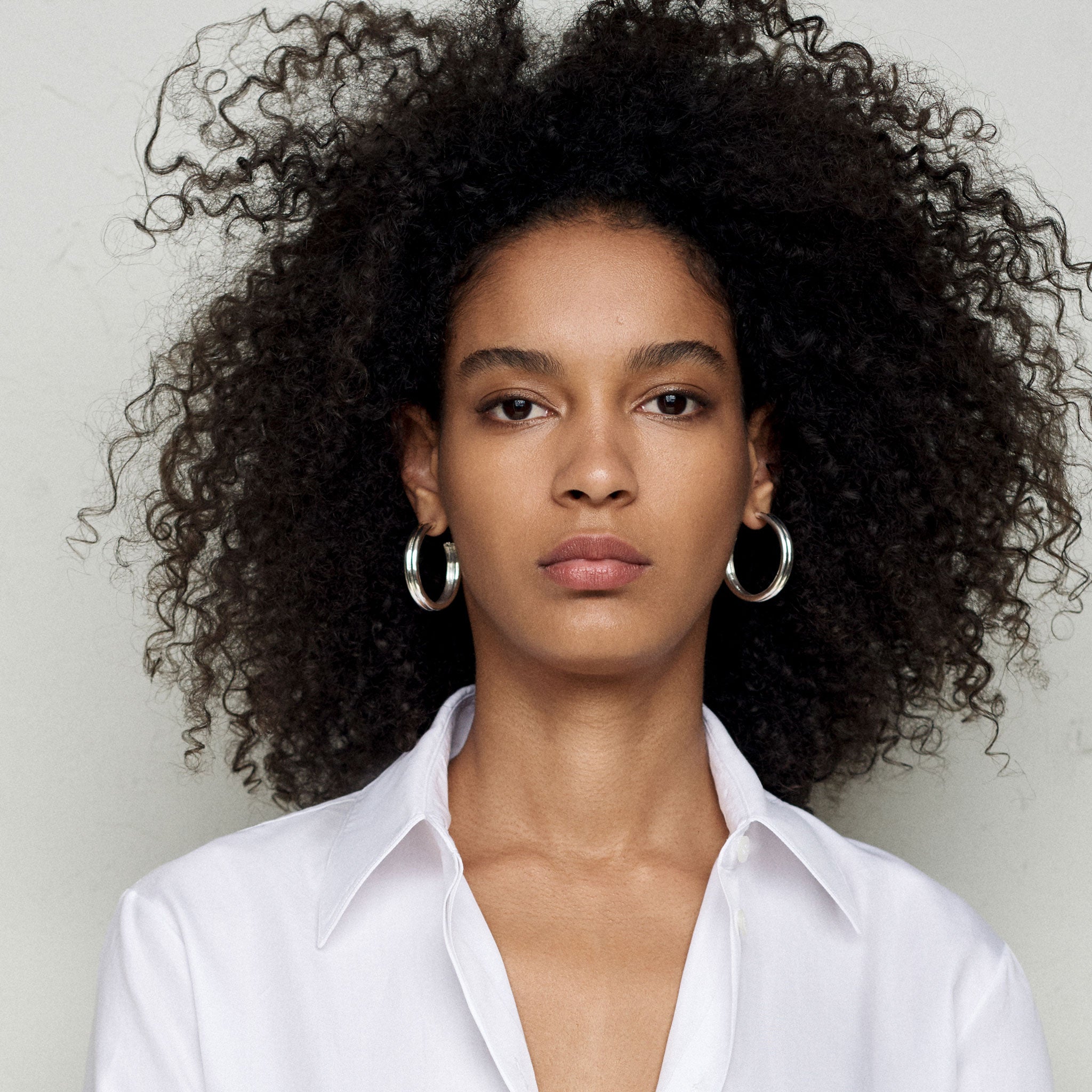 Woman wearing AGMES 0.925 sterling silver double ridged large hoop earrings.