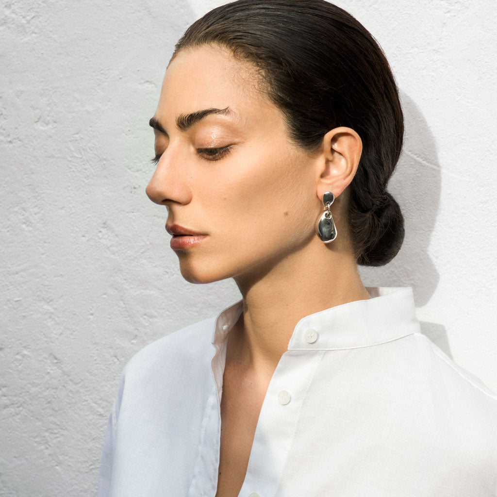Woman wearing AGMES 0.925 sterling silver sculpted round drop earrings.
