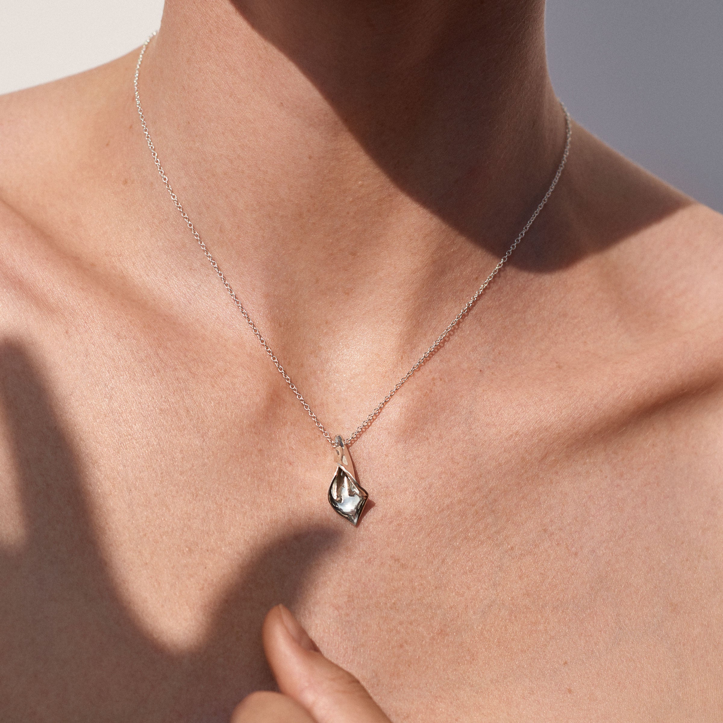 Person wearing AGMES .925 Sterling Silver Mini Calla Pendant paired with Sterling Silver Chain necklace. 