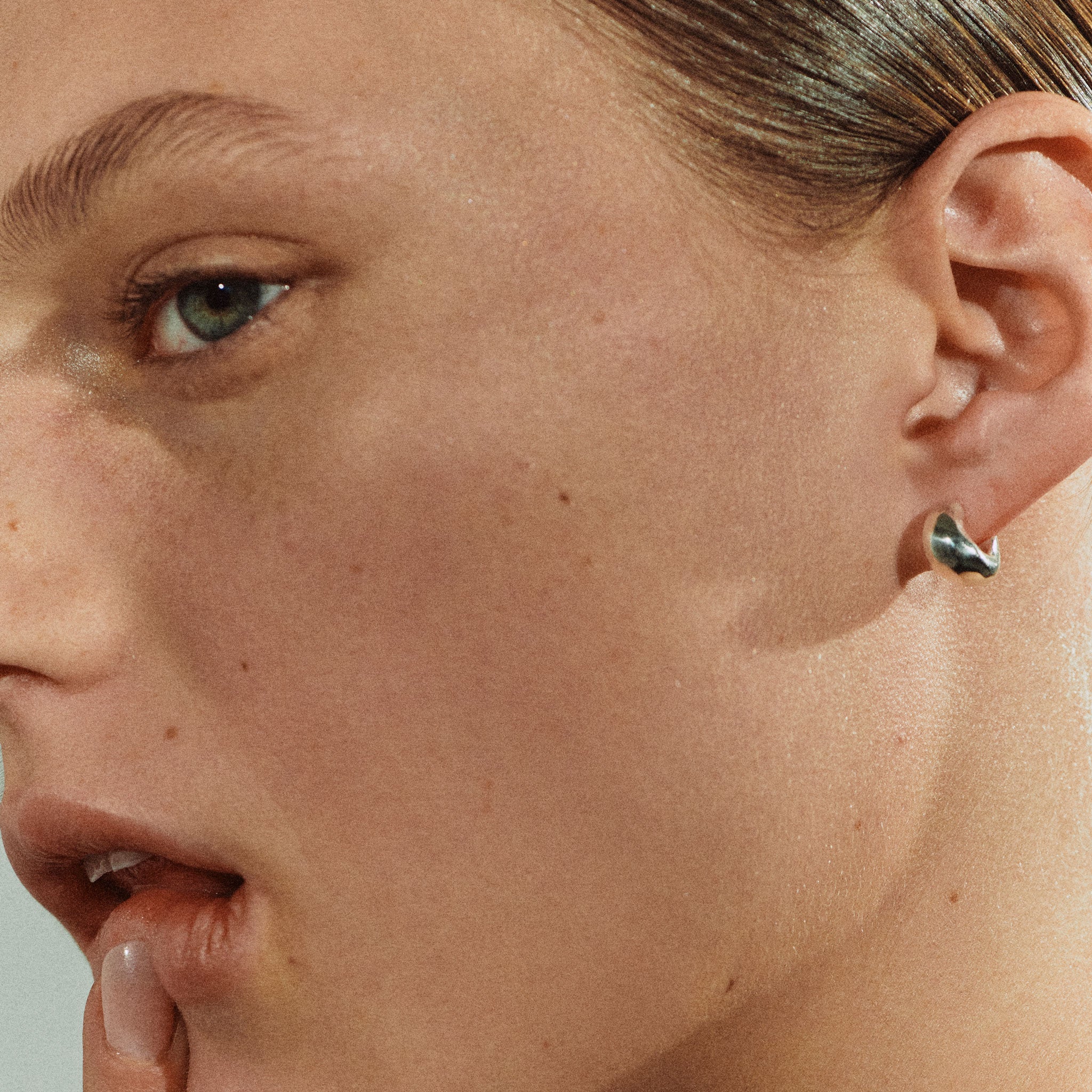 Woman wearing AGMES 0.925 sterling silver thick hoop huggie earrings.