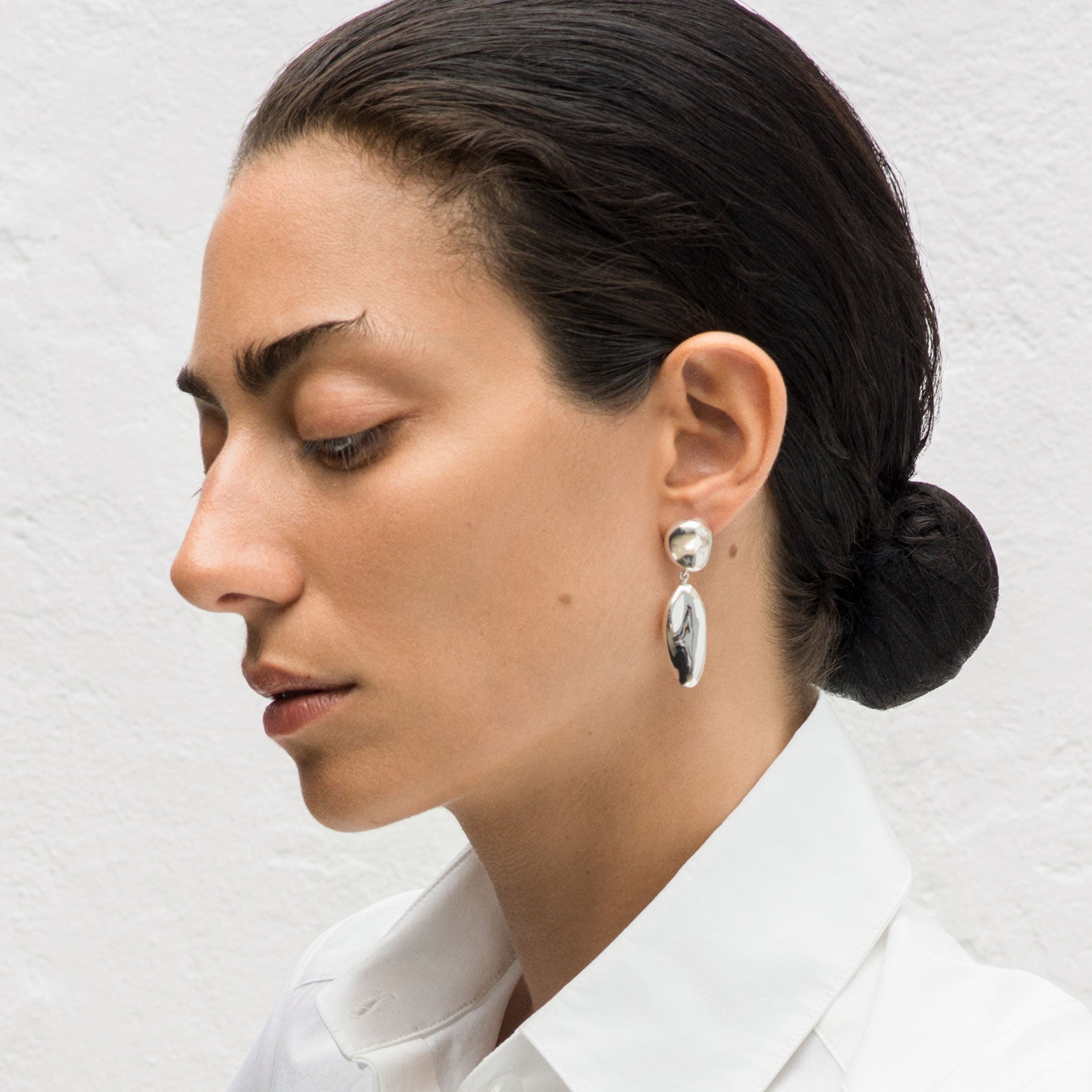 Woman wearing AGMES 0.925 sterling silver sculpted drop earrings.