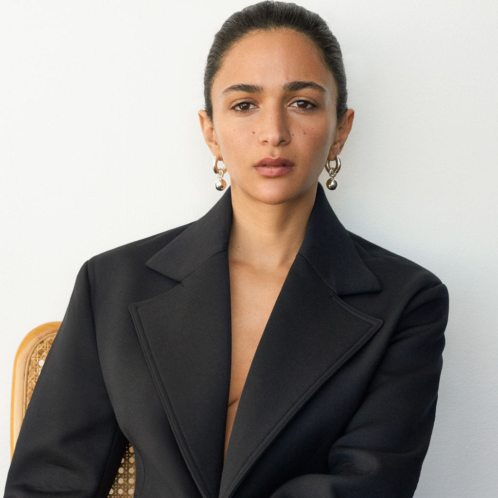 Woman wearing AGMES 0.925 sterling silver hinged hoop earrings with 18k yellow gold round embellishments.