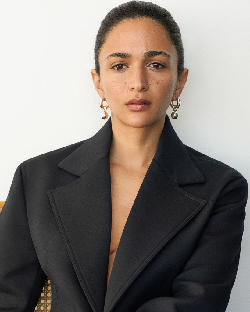 Woman wearing AGMES 0.925 sterling silver hinged hoop earrings with 18k yellow gold round embellishments.