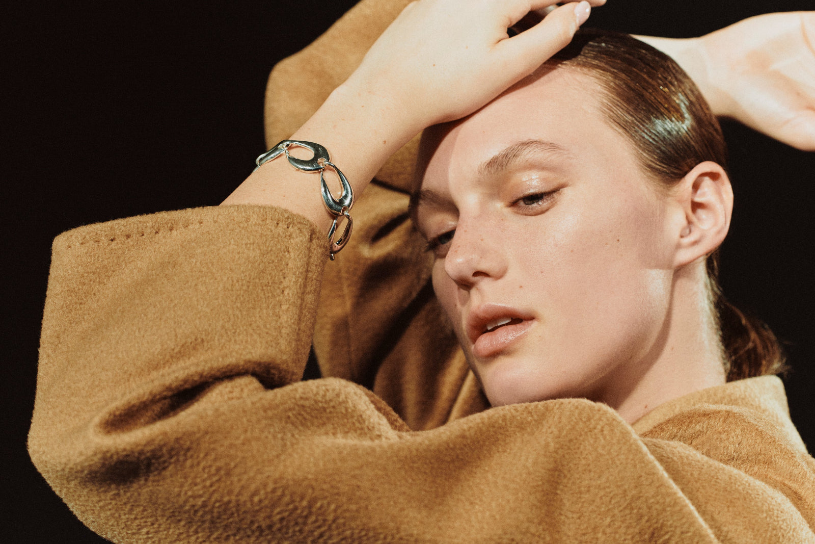 Model wearing AGMES .925 sterling silver sculptural link Tilda bracelet and tan coat.