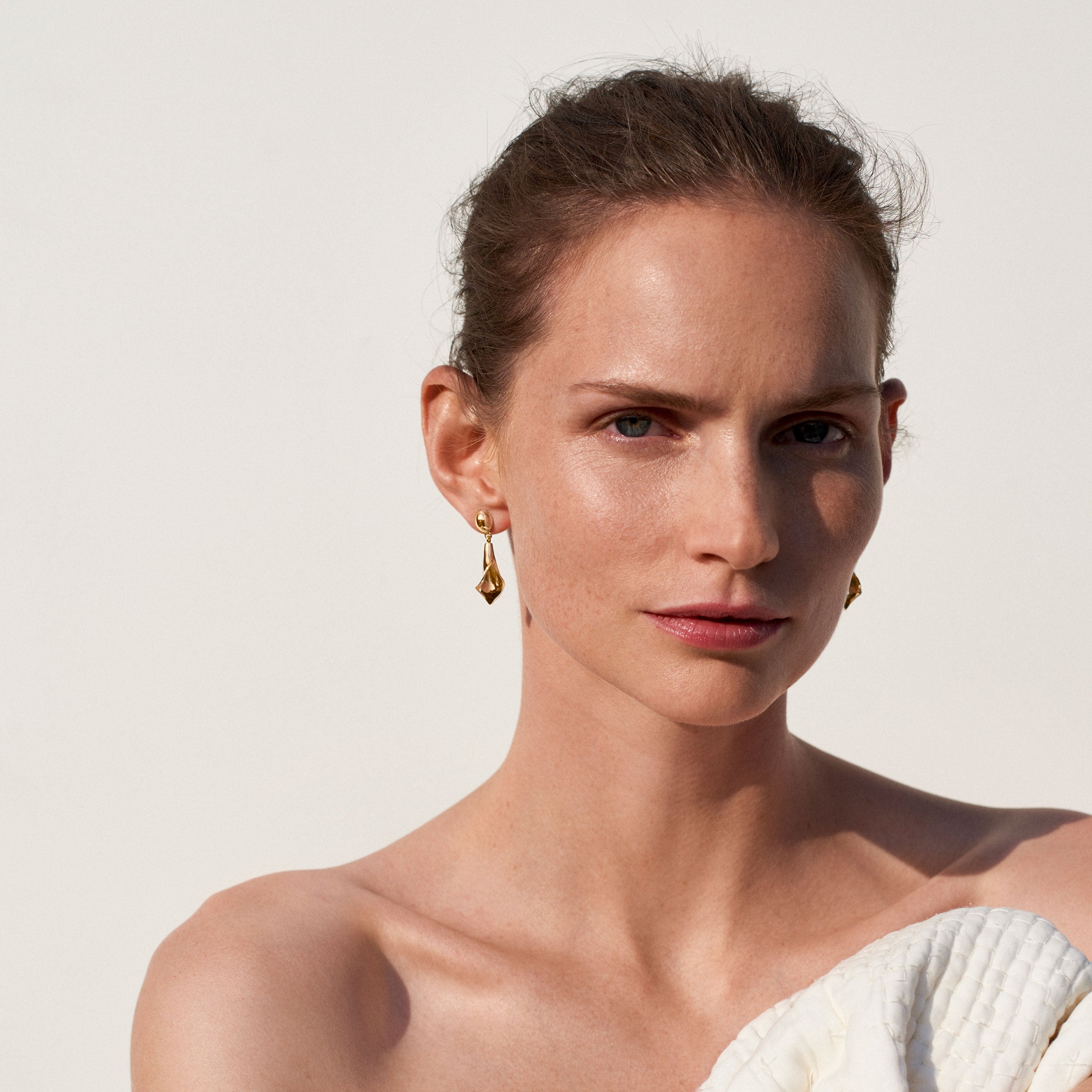 Woman wearing AGMES 18k gold vermeil mini calla lily inspired drop earrings.