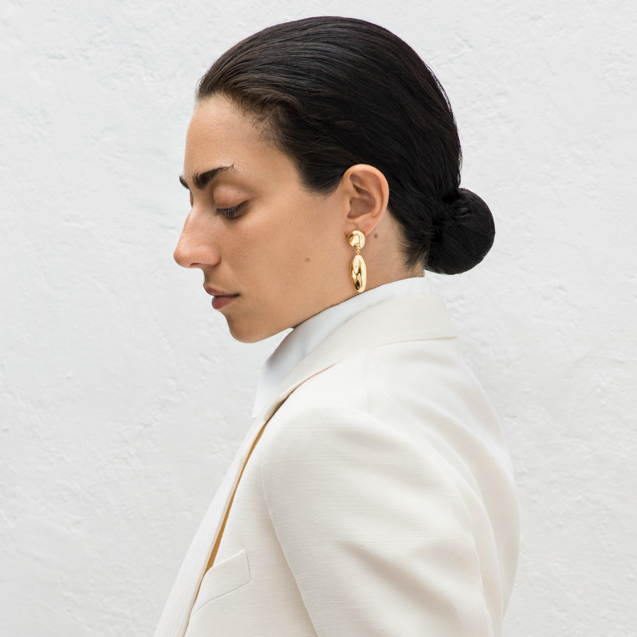 Woman wearing AGMES 18k gold vermeil sculpted drop earrings.