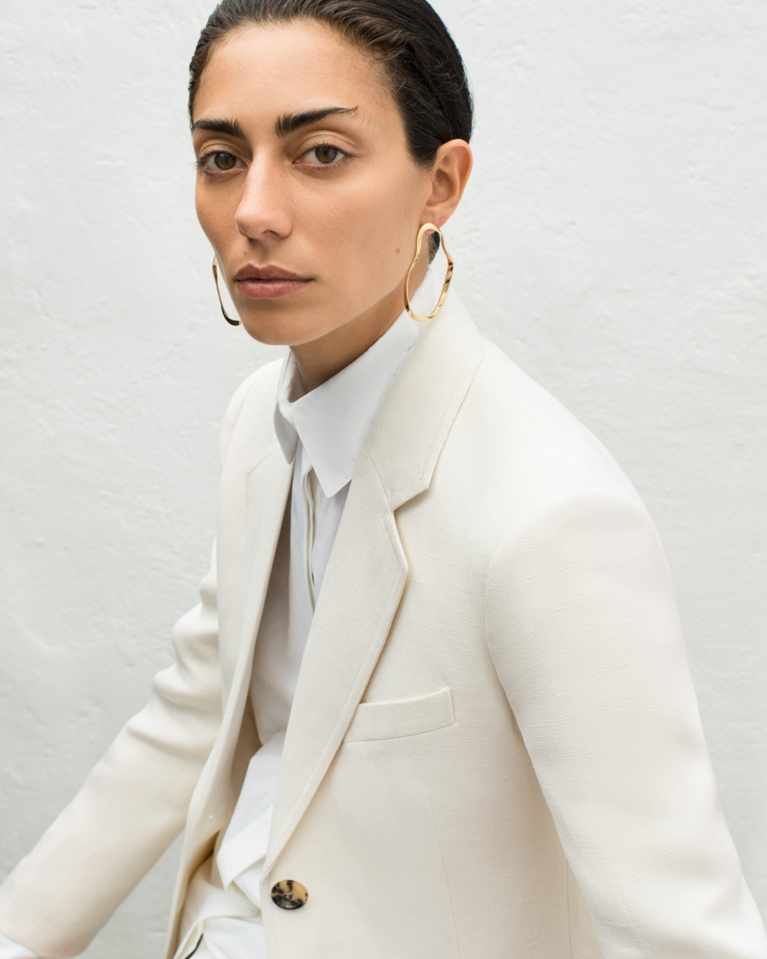 Woman wearing AGMES 18k gold vermeil sculptural wavy round hoop earrings.